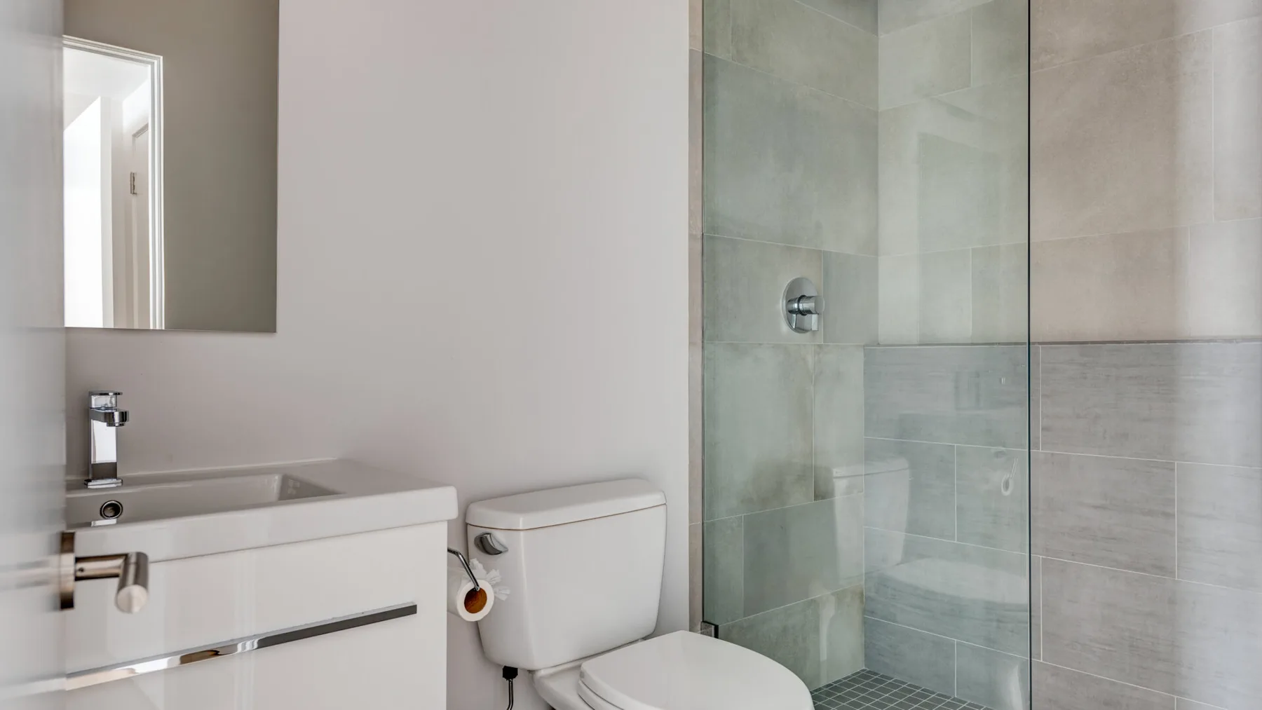A bathroom with a sink, toilet, and glass-enclosed shower.