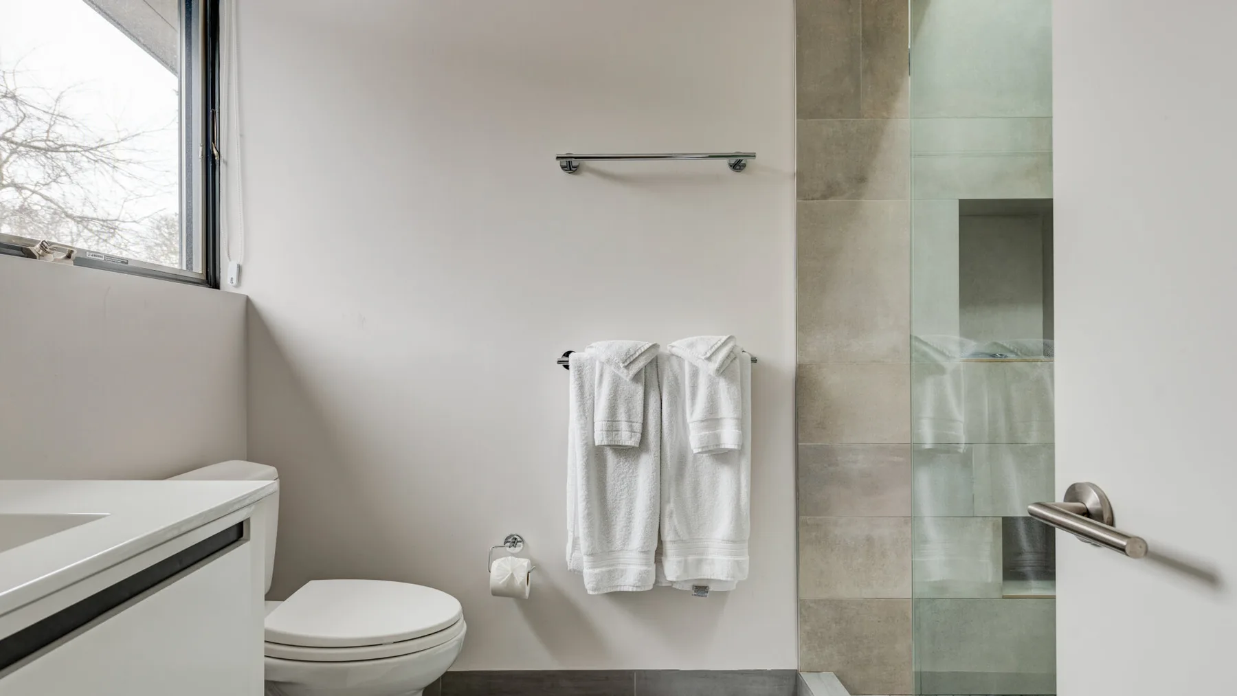 A bathroom with a sink, toilet, and towels hanging on the wall.