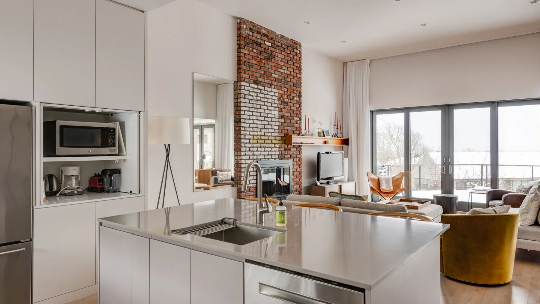 An open-plan kitchen and living area with a large island and exposed brick fireplace.