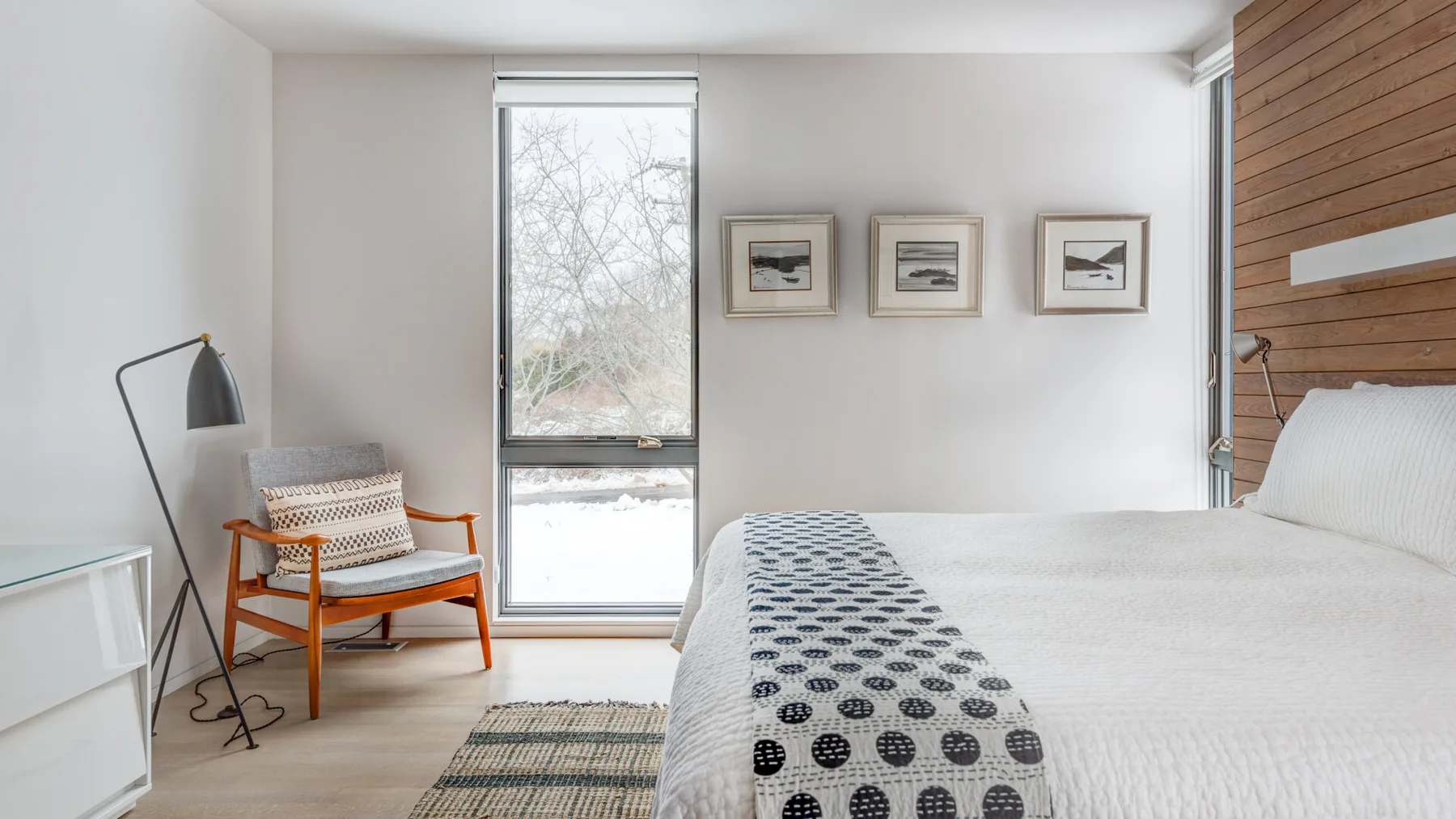 A bright bedroom with a bed, patterned runner, and window.