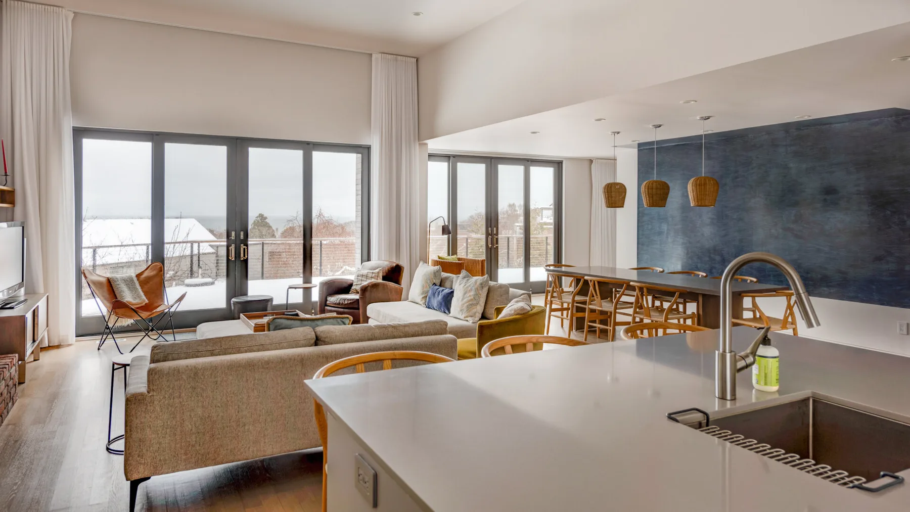 An open-plan living and dining area has large windows and a kitchen island.