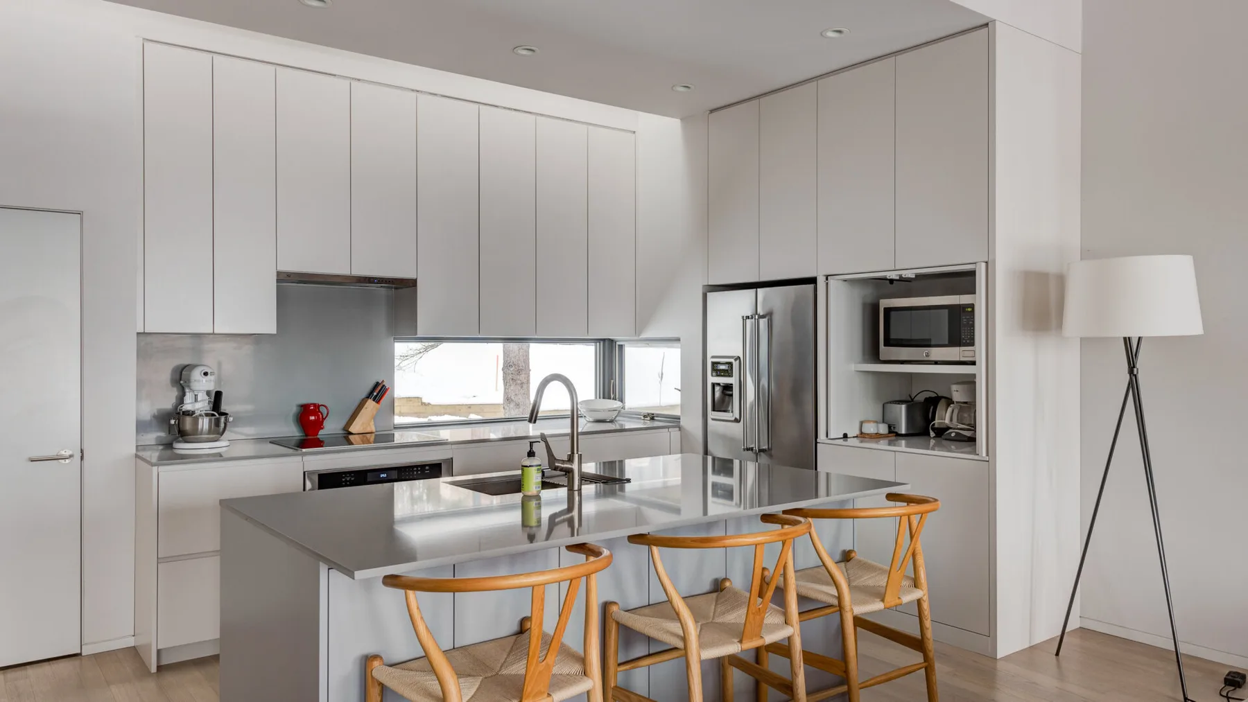 A bright modern kitchen with a central island and tall white cabinets.