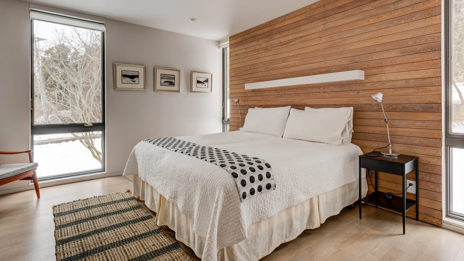 A bedroom with a neatly made bed and a wood-paneled wall.