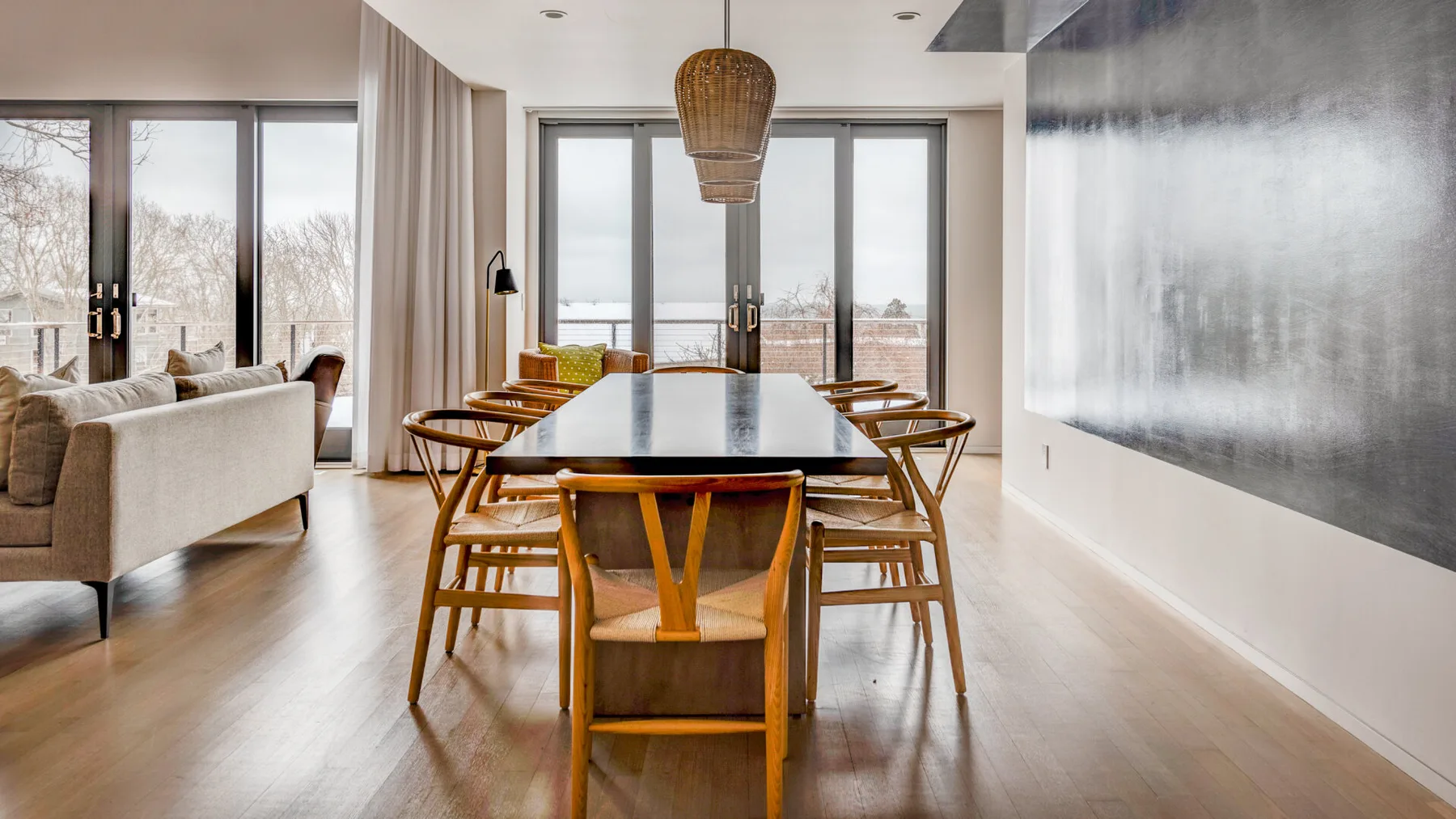 A dining area with a long table and chairs beside large windows.