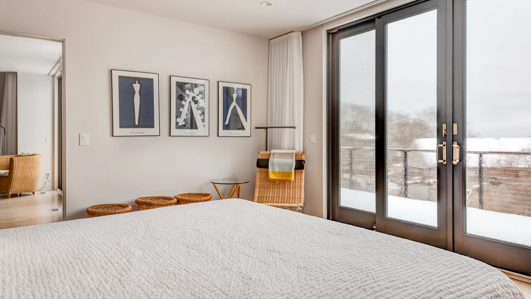 A bright bedroom with a neatly made bed and glass doors opening to a balcony.