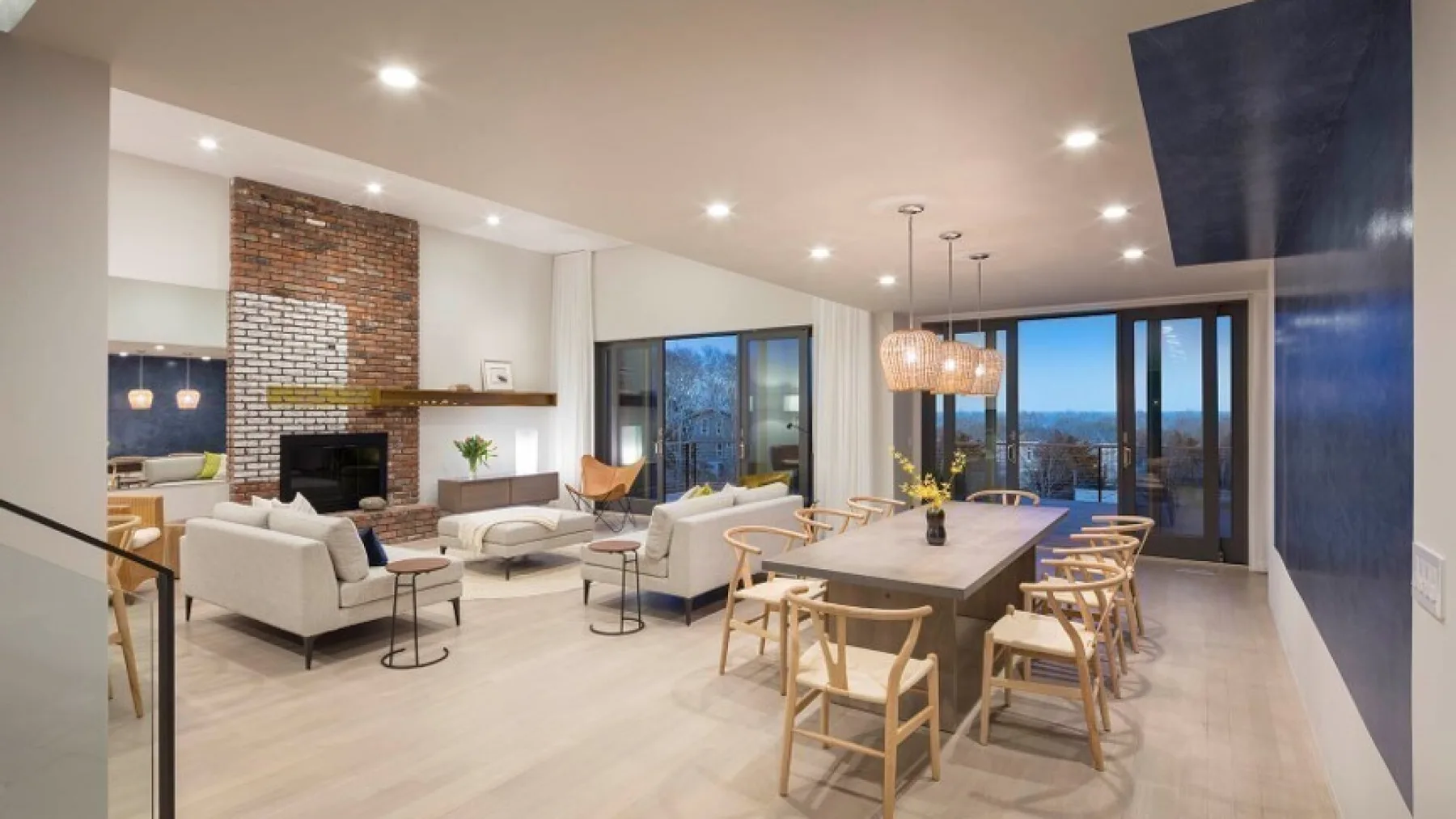 A bright open-plan living and dining room with seating around a long table.