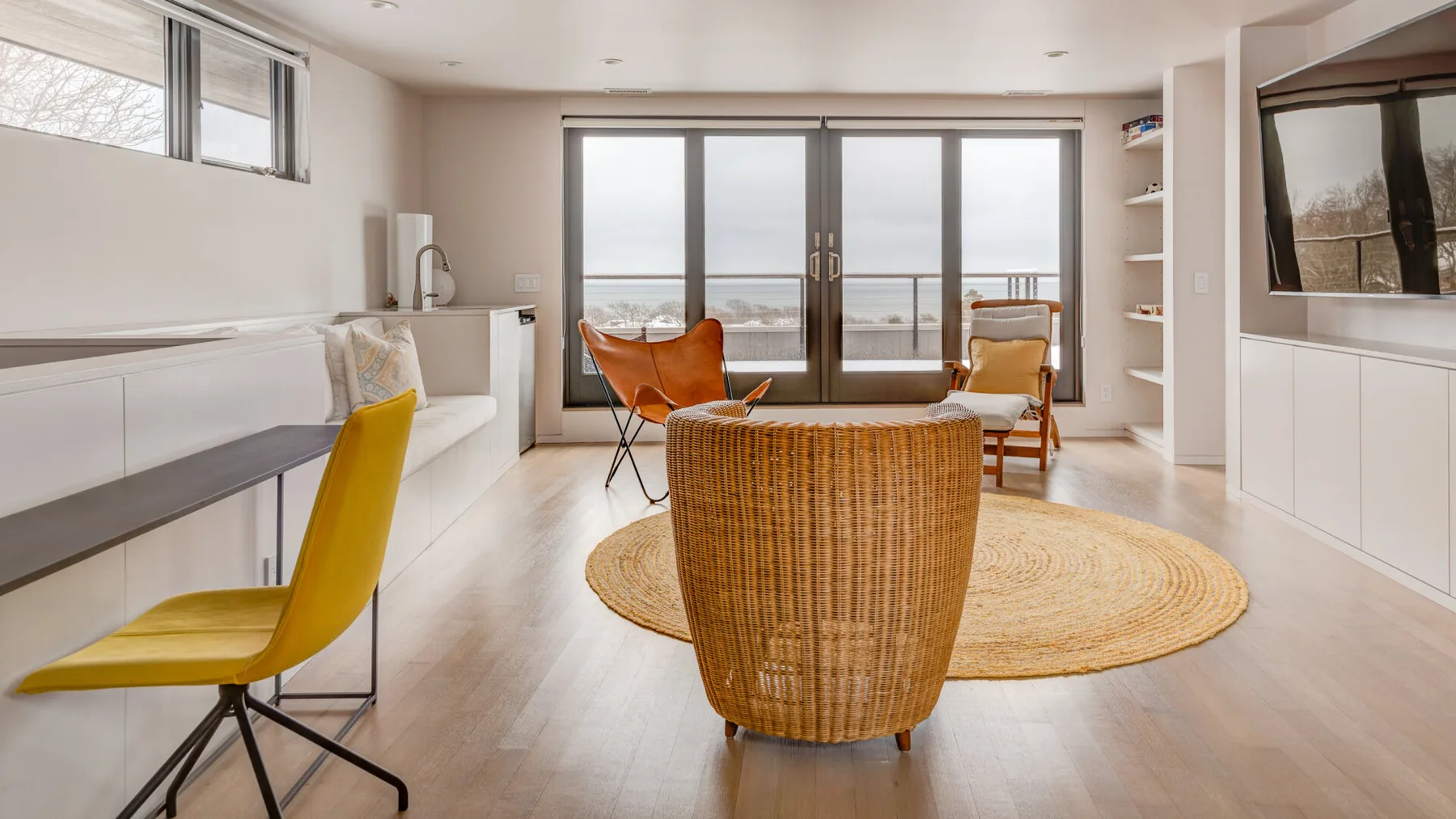 A bright living room with seating around a woven chair and a round rug.