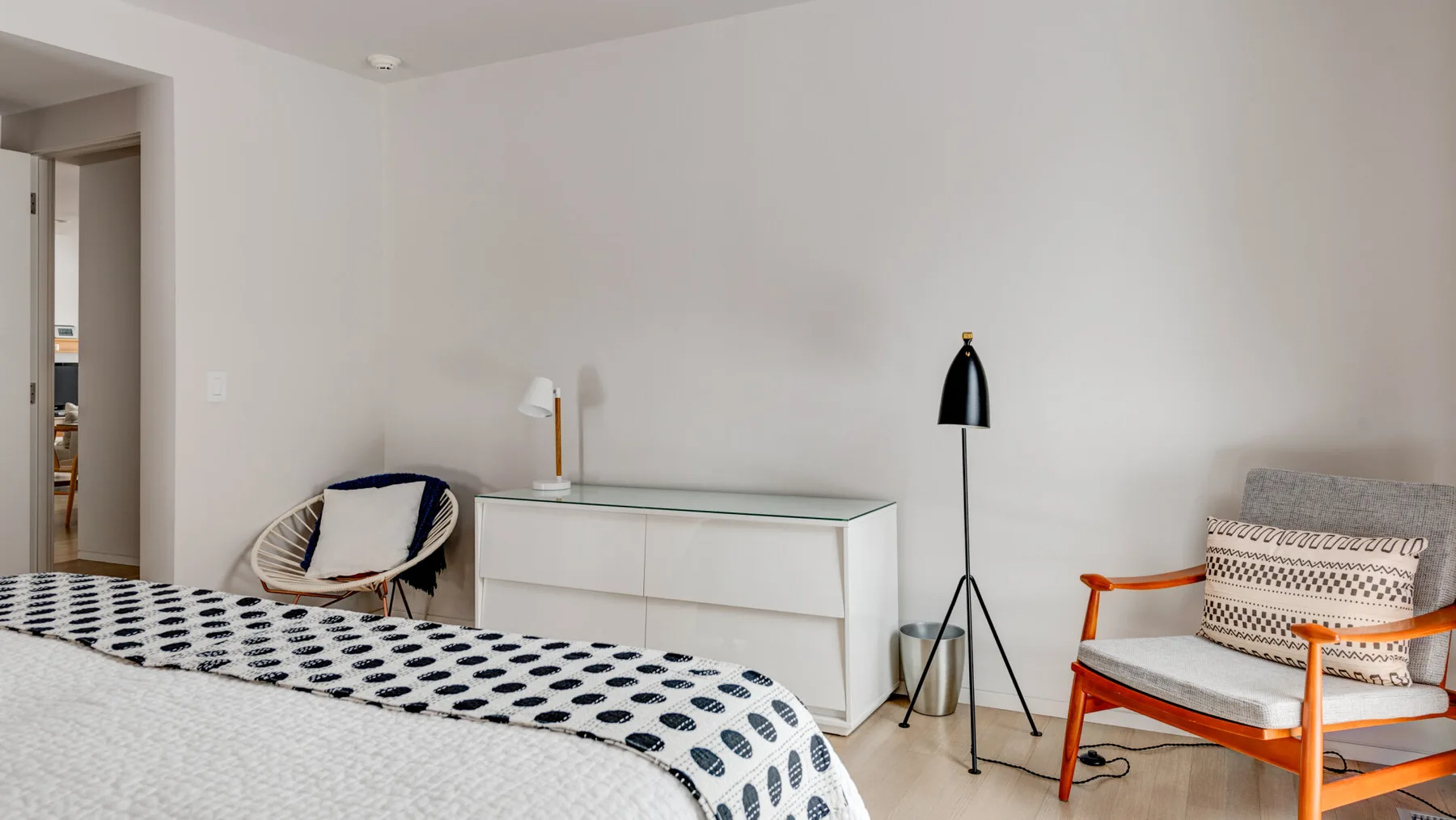 A bedroom with a bed, bedside cabinet, and reading lamps.