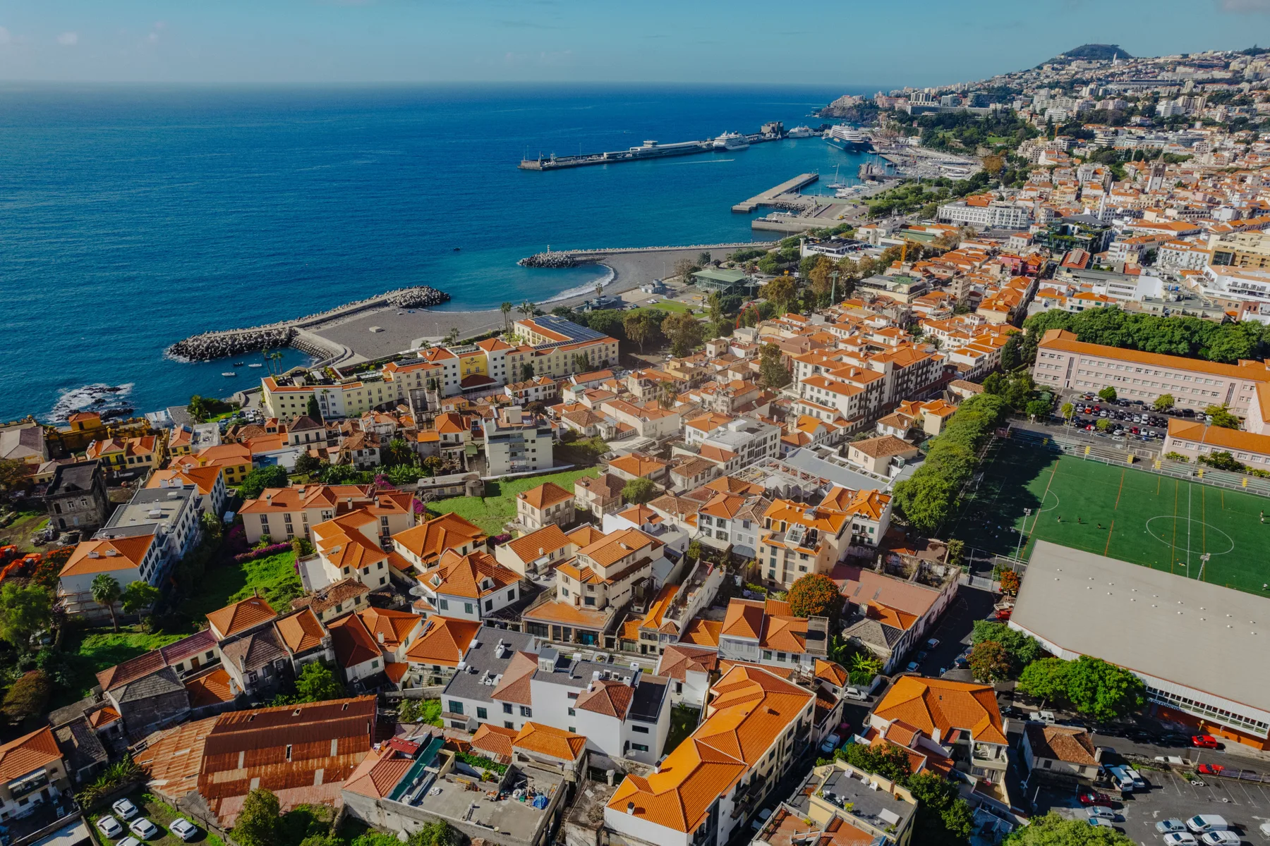Vista aérea de una ciudad costera con edificios densos, un puerto y el mar.