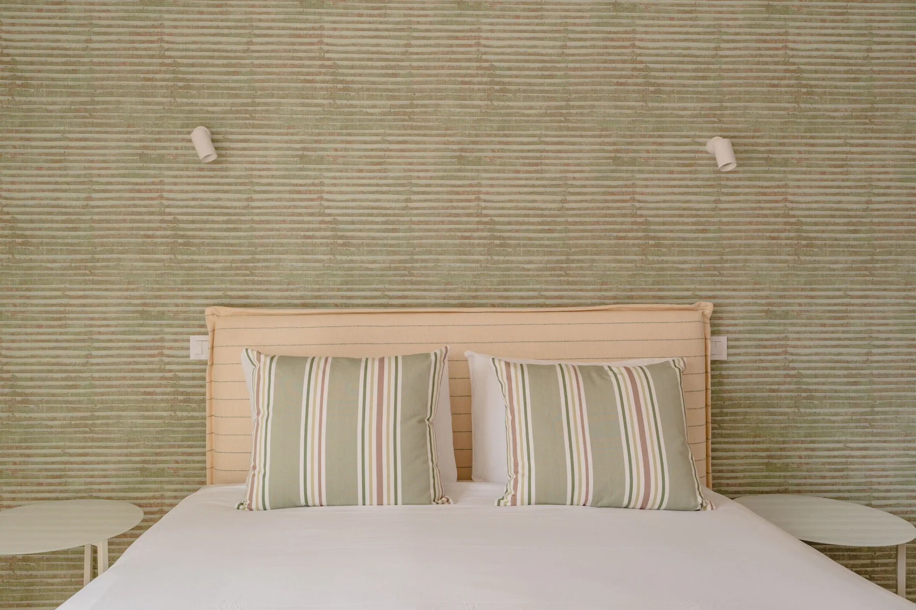 Un dormitorio con una cama y almohadas a rayas frente a una pared texturizada.