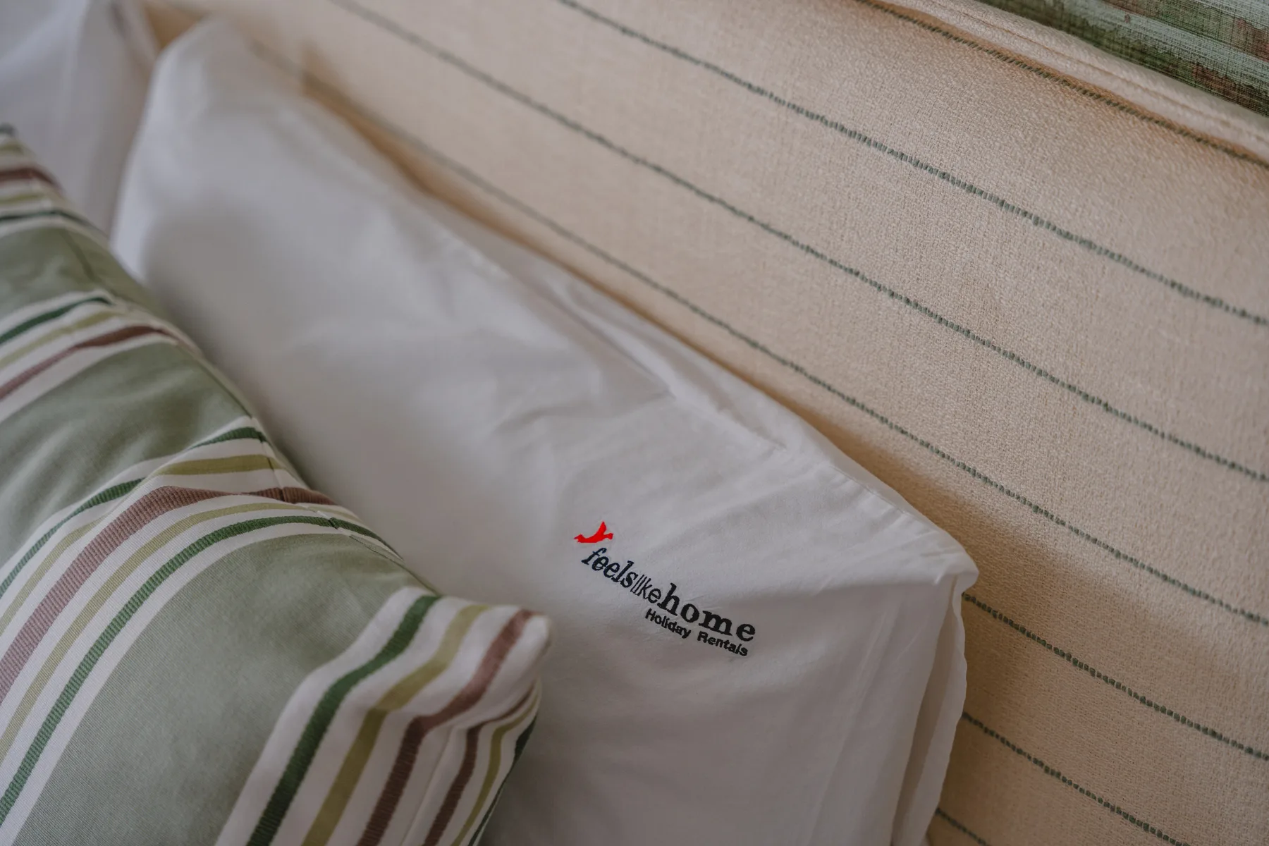 Una cama con ropa de cama blanca y un cojín decorativo a rayas.