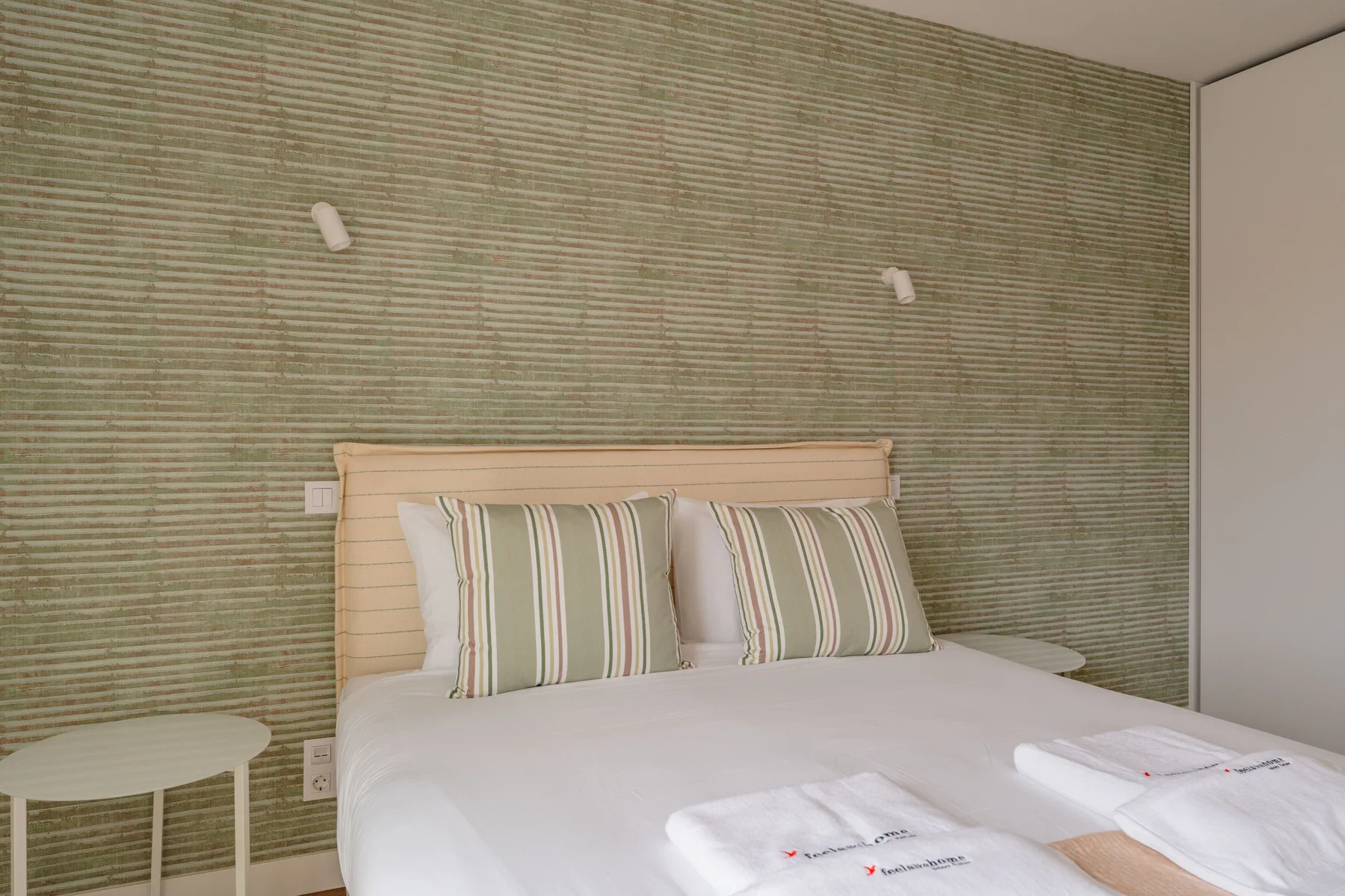 Dormitorio con una cama, almohadas a rayas y pequeñas luces de pared.