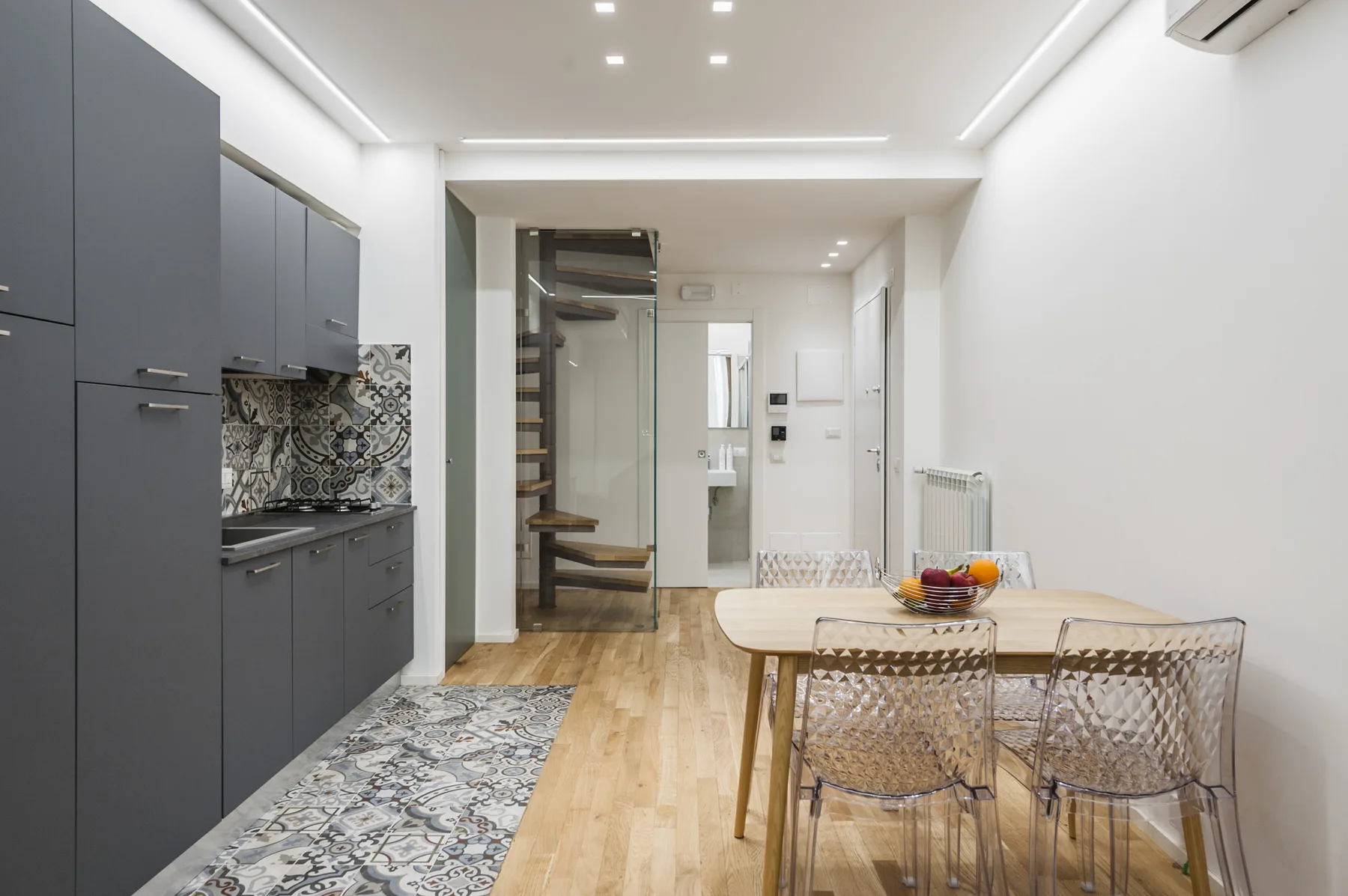 Cocina y comedor modernos con una mesa, sillas y suelo estampado.
