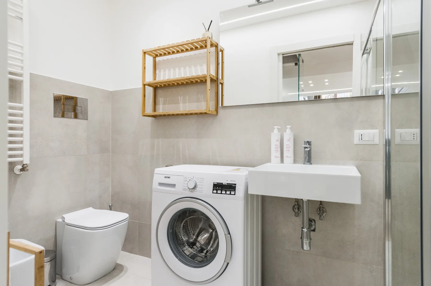 Un baño luminoso con inodoro, lavadora y lavabo de pared.