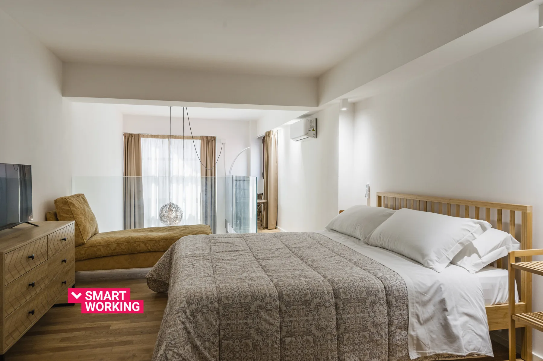 Un dormitorio luminoso con una cama grande y una zona de estar junto a la ventana.