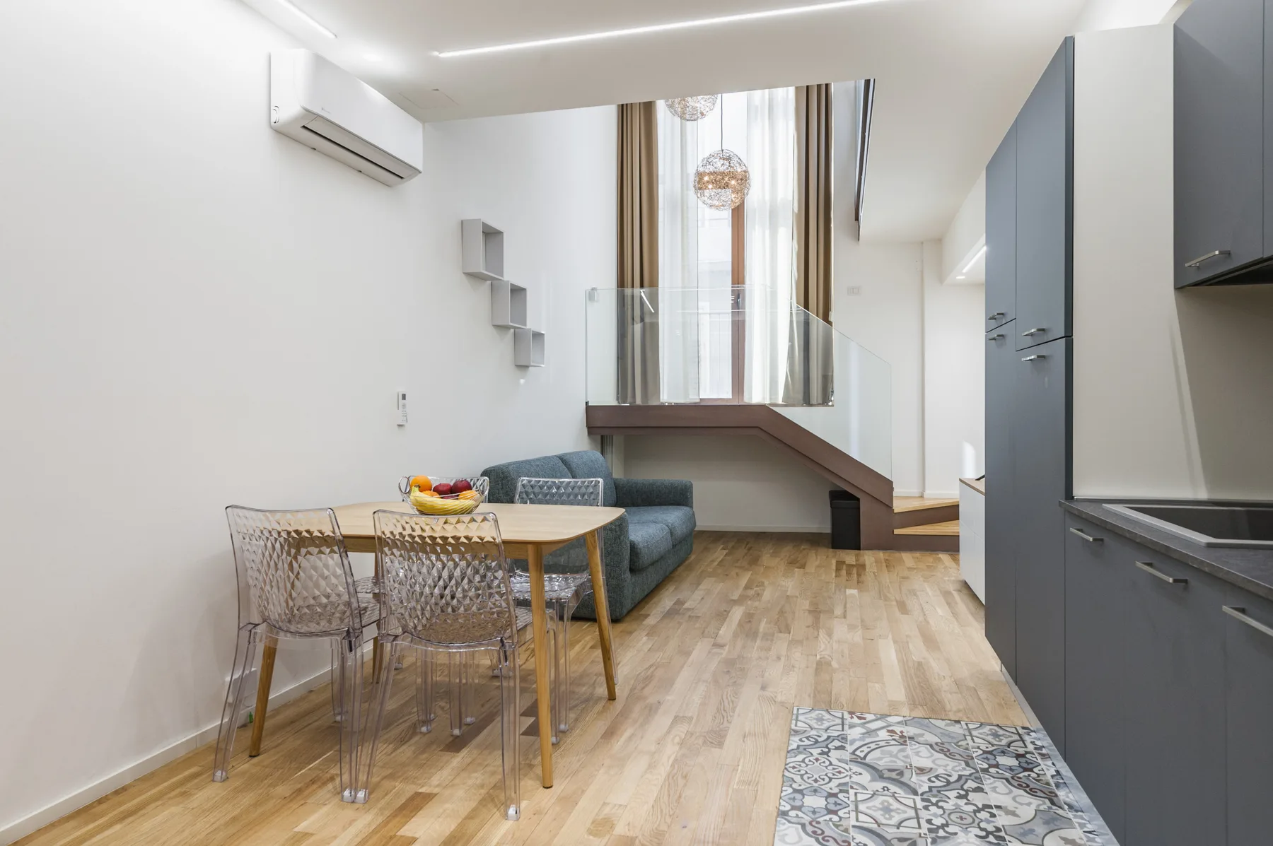 Una zona moderna de estar y comedor con mesa, asientos y ventanas altas.