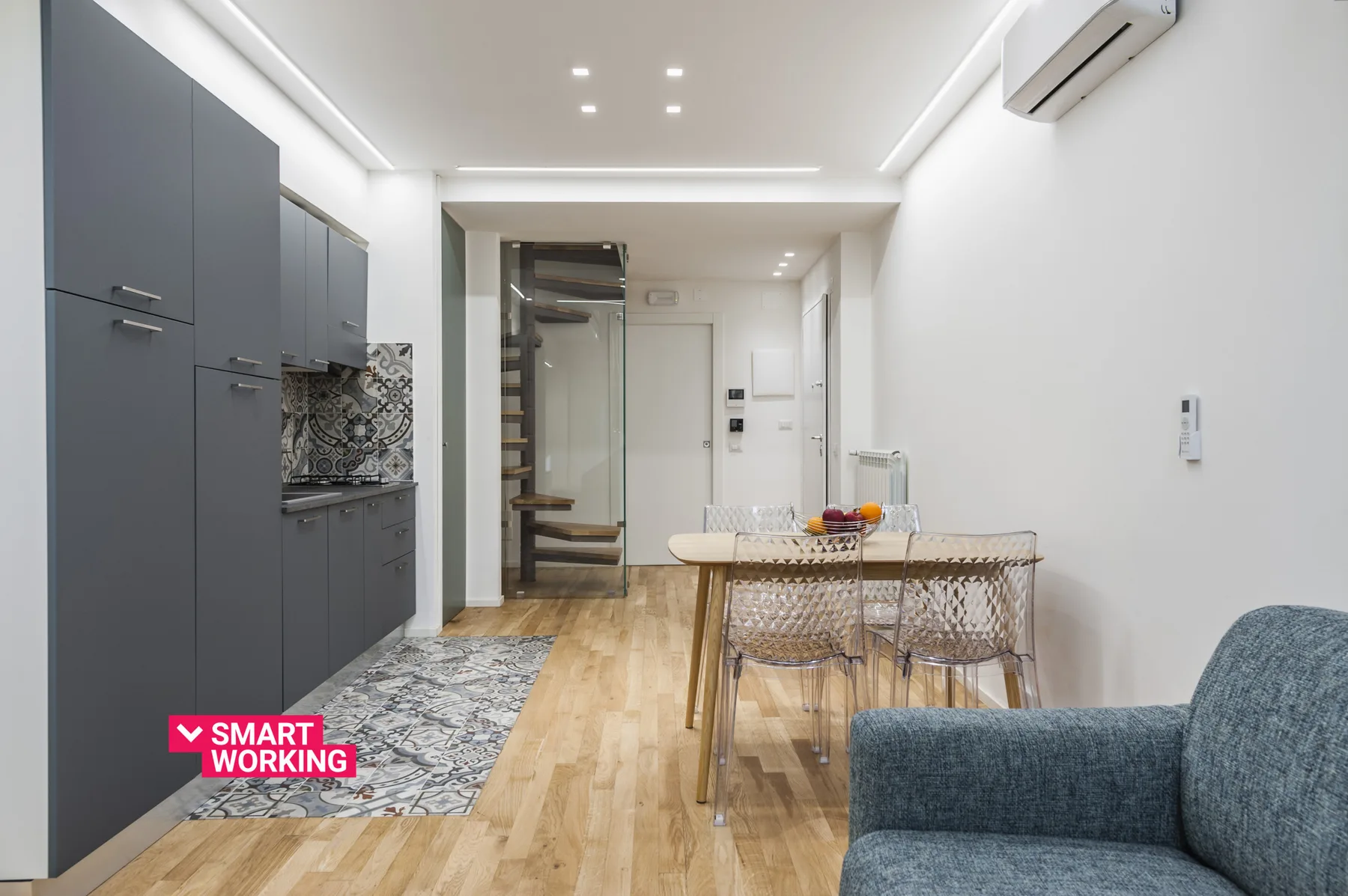 Una cocina y comedor modernos con gabinetes oscuros, una mesa y asientos.