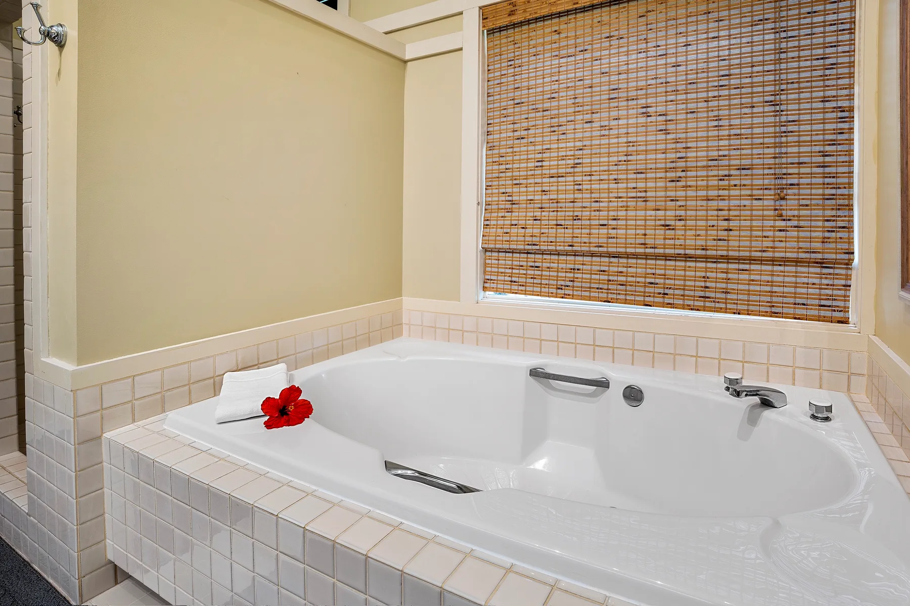 Un baño con azulejos y una gran bañera blanca bajo una ventana.