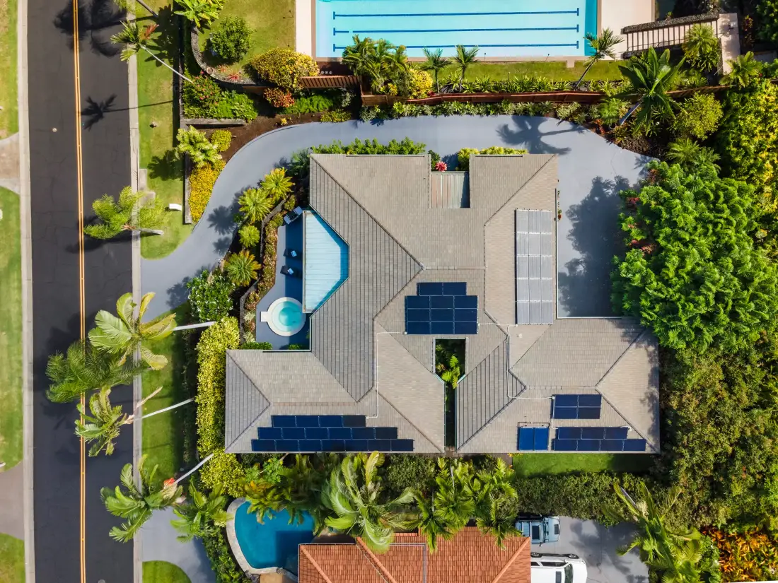 Vista aérea de una casa con paneles solares en el techo y una piscina.