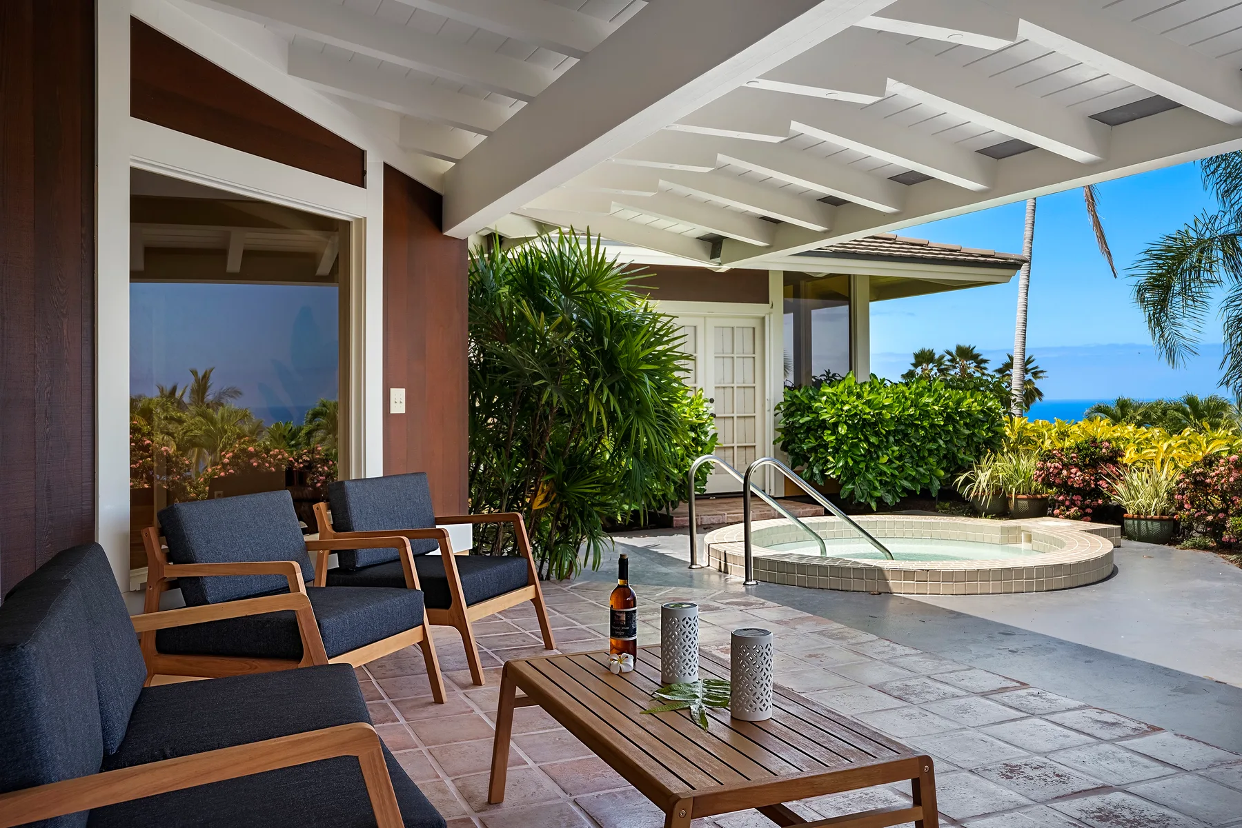 Un patio cubierto con asientos y una pequeña piscina con vista al mar.