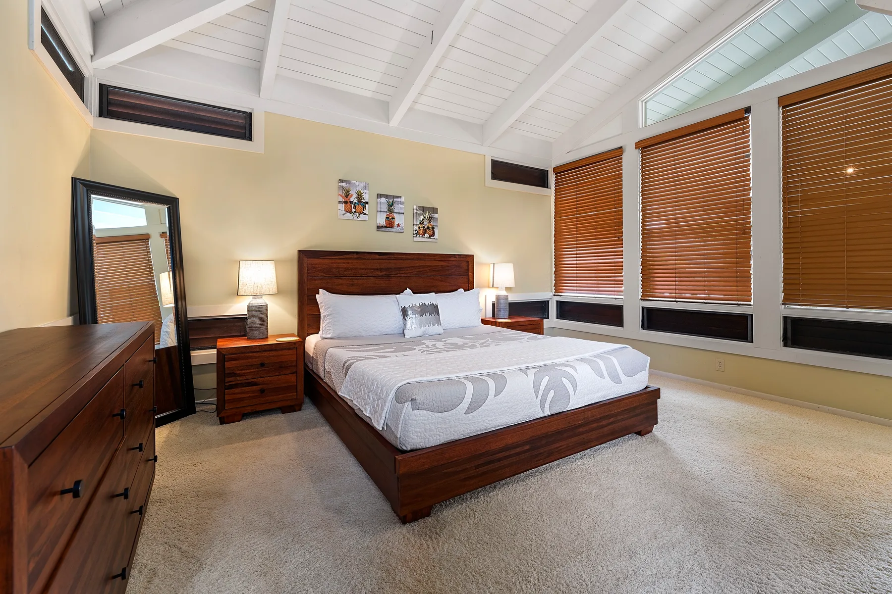 Un dormitorio con una cama de madera, mesitas de noche y ventanas con persianas.