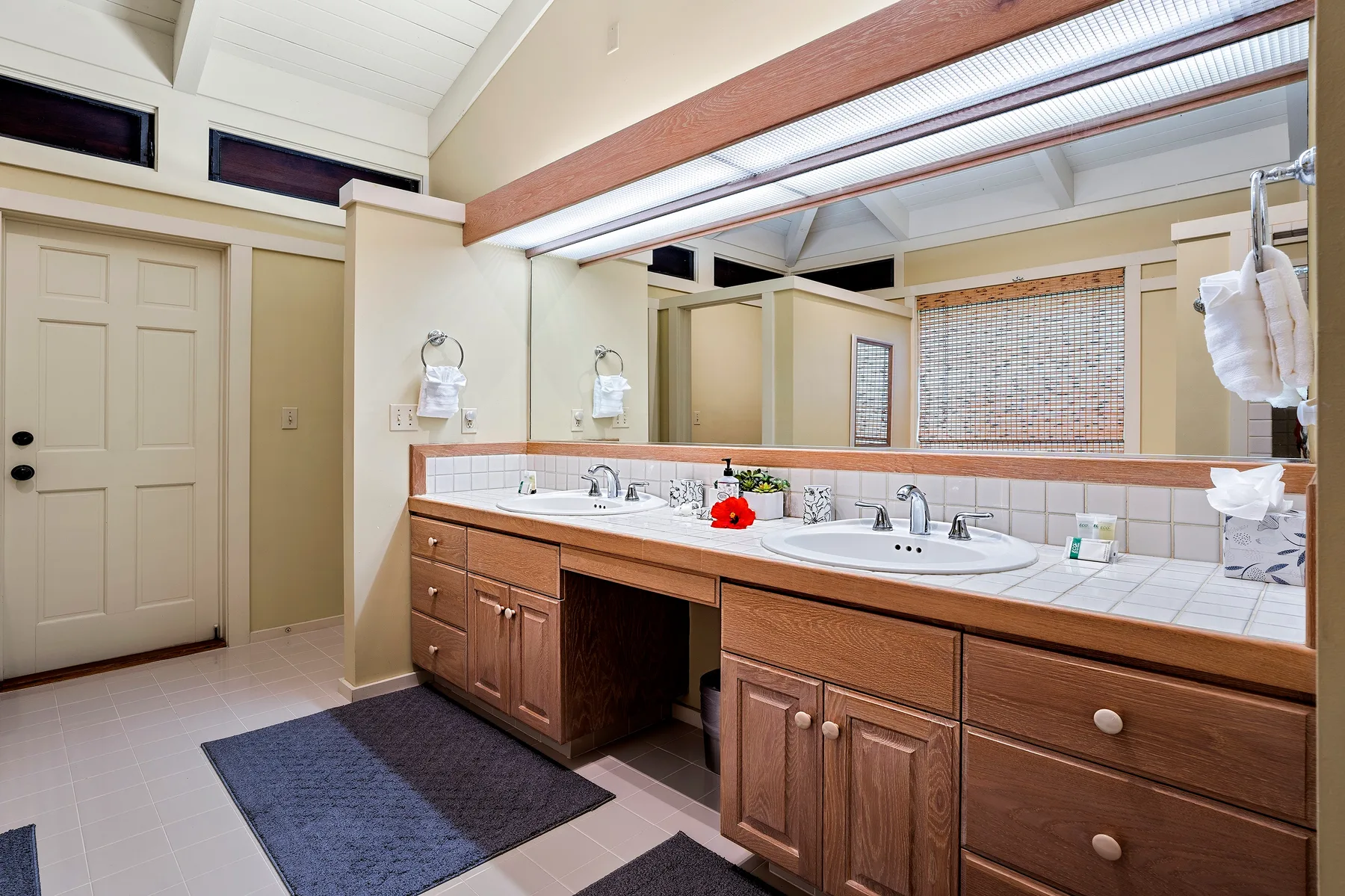 Un tocador de baño con dos lavabos, gabinetes de madera y un espejo grande.