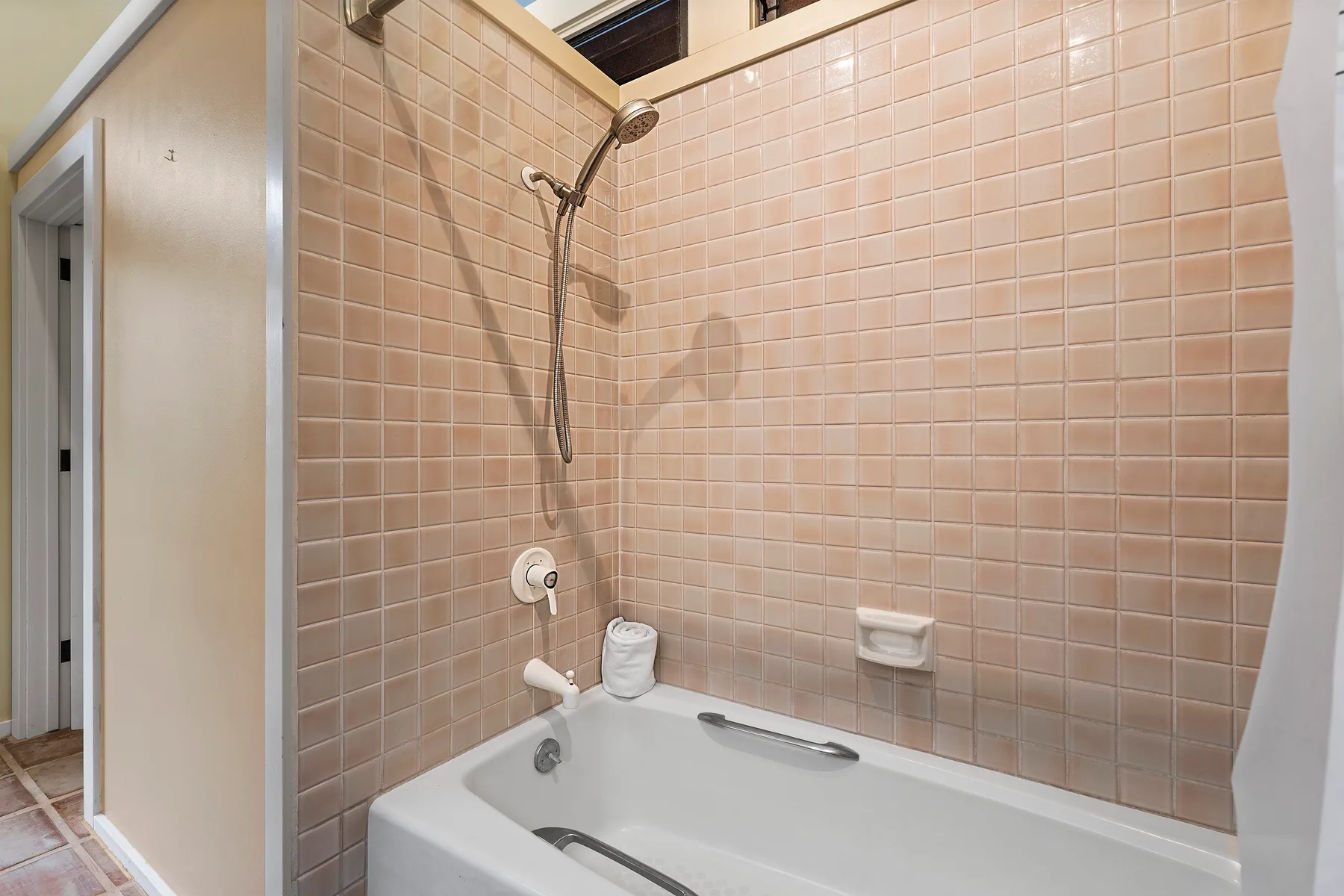 Un baño con azulejos, bañera y ducha montada en la pared.