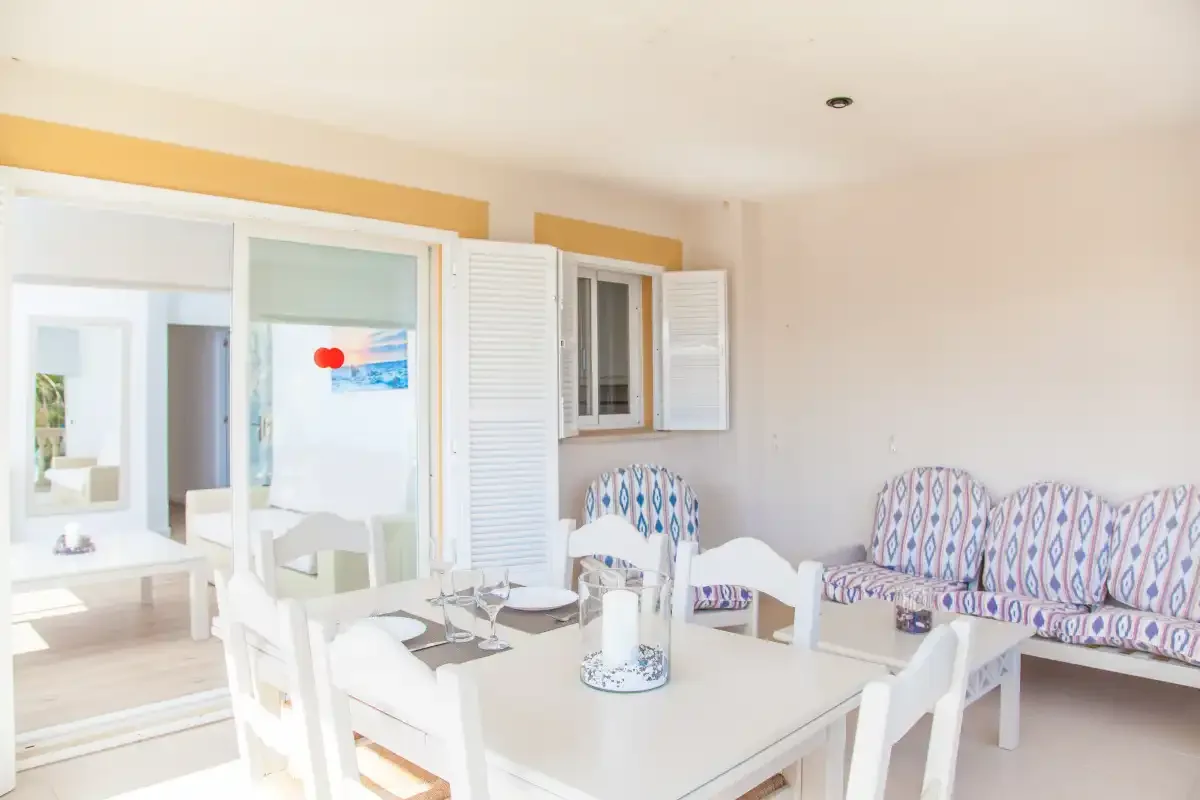 Un comedor luminoso con una mesa blanca y asientos estampados.