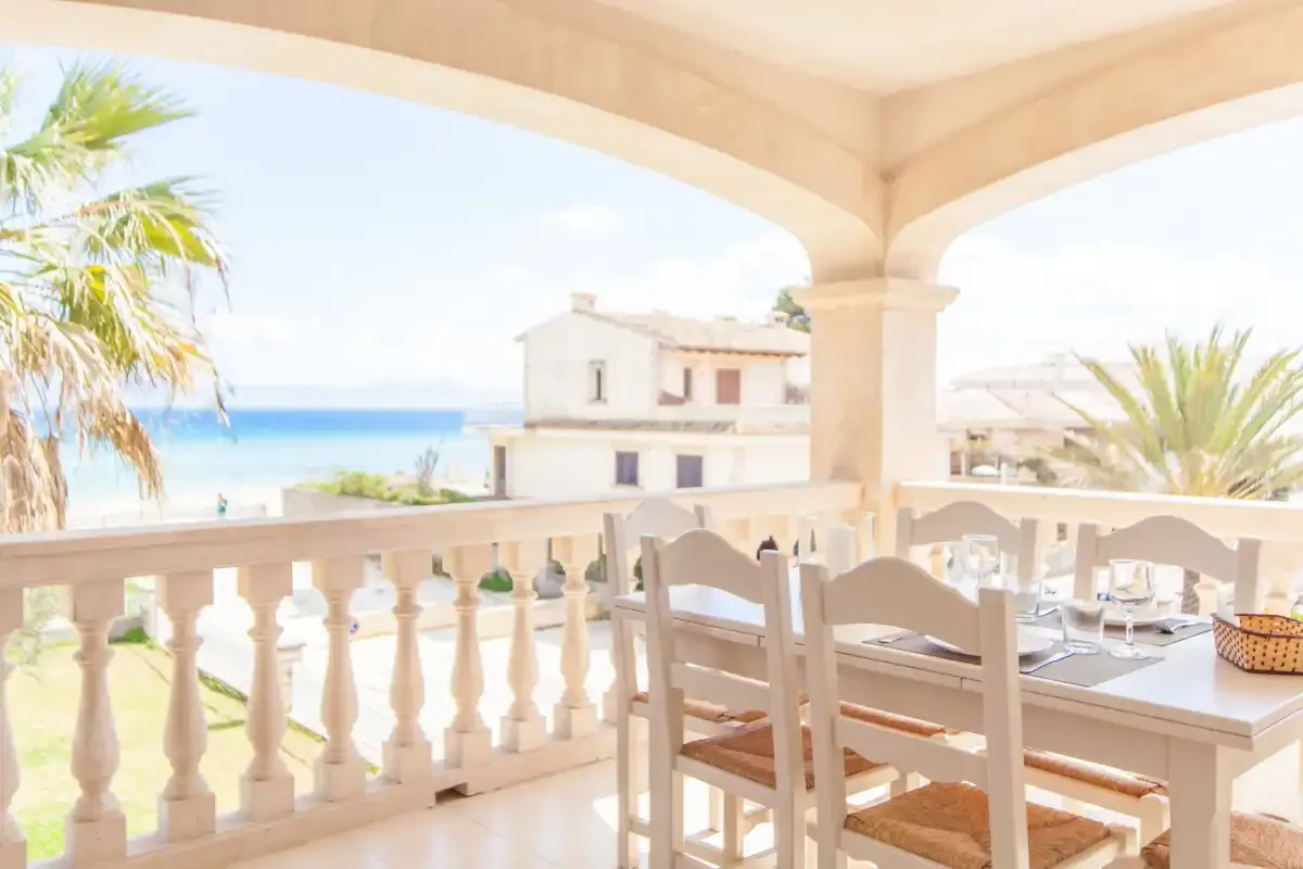 Una terraza cubierta con comedor da al mar, con una mesa y sillas junto a la balaustrada.