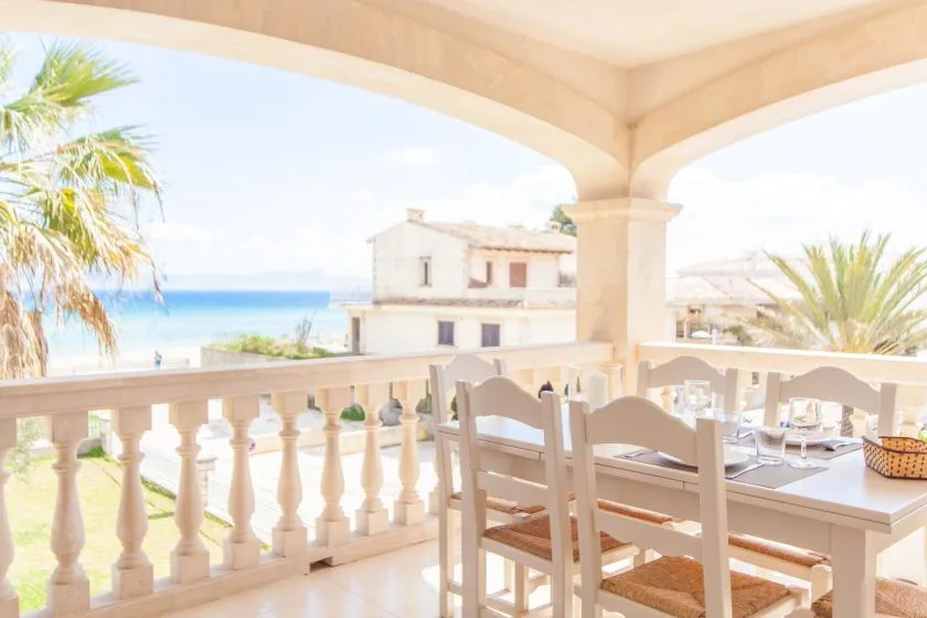 Una zona de comedor en una terraza cubierta da al mar y a edificios cercanos.