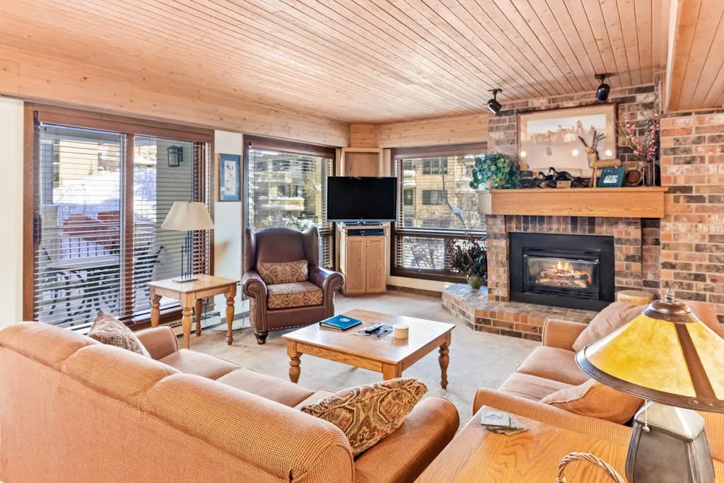 A living room with seating, a television, and a brick fireplace.