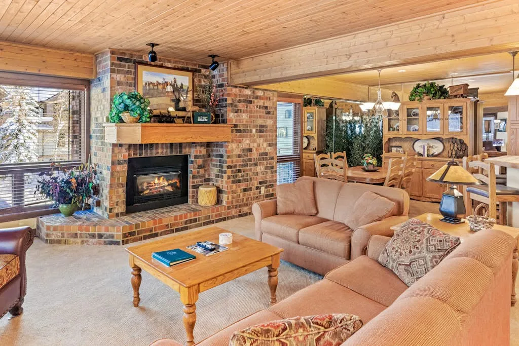 A wood-paneled living room with a brick fireplace and seating.