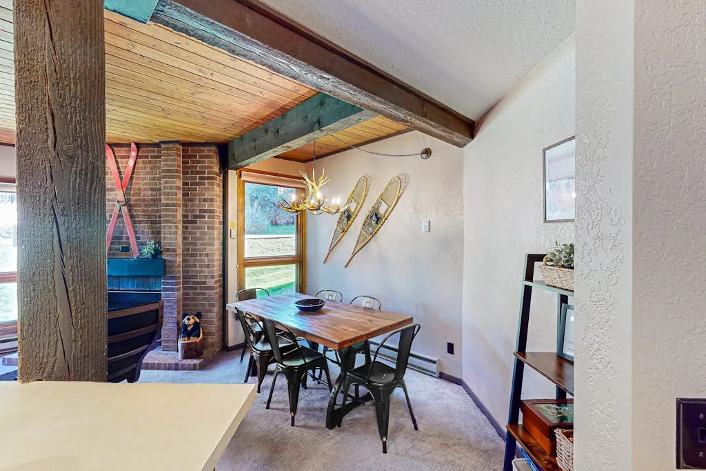 A dining area with a wooden table and chairs beneath a beamed ceiling.