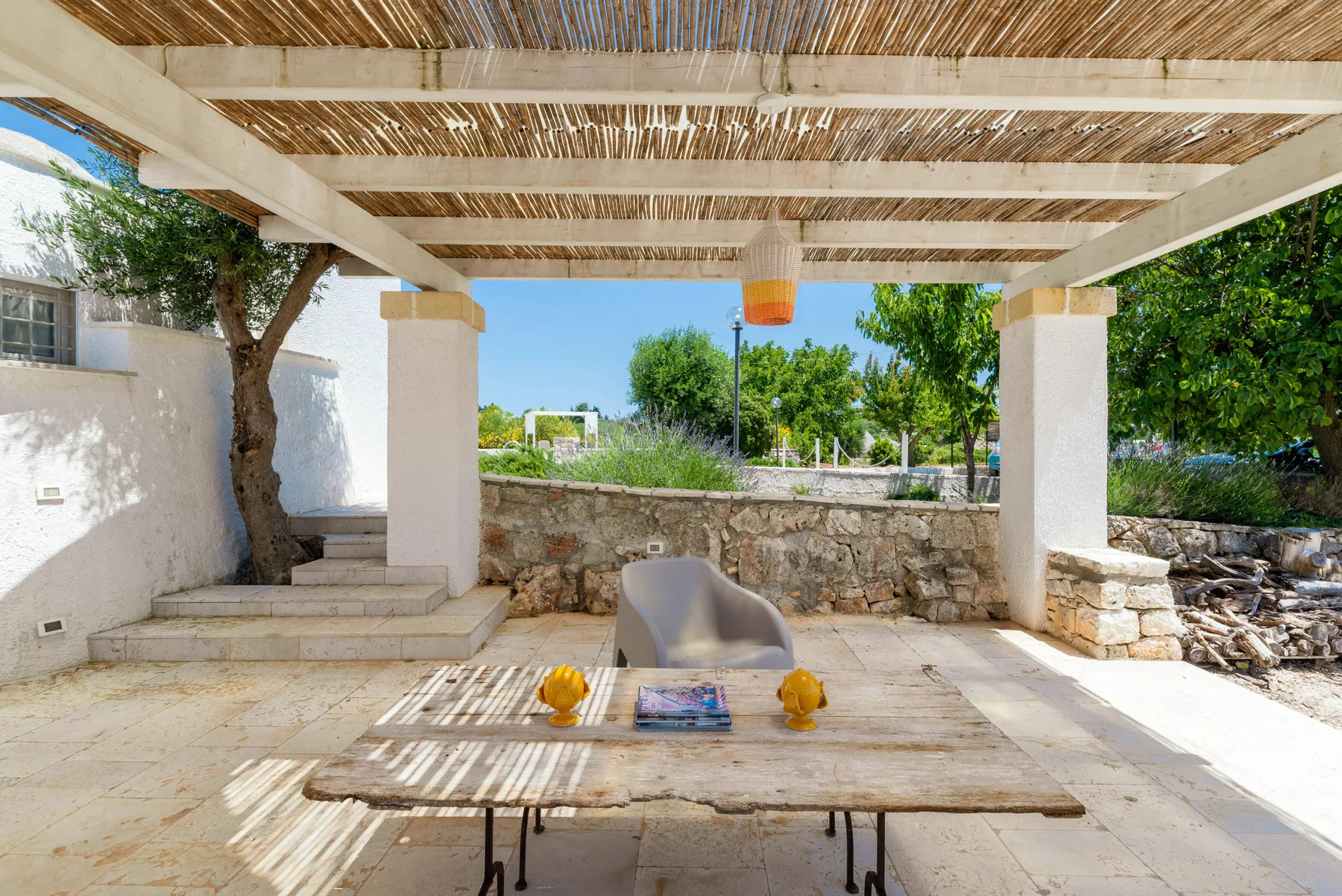 A shaded outdoor patio with a table and seating beneath a wooden pergola.