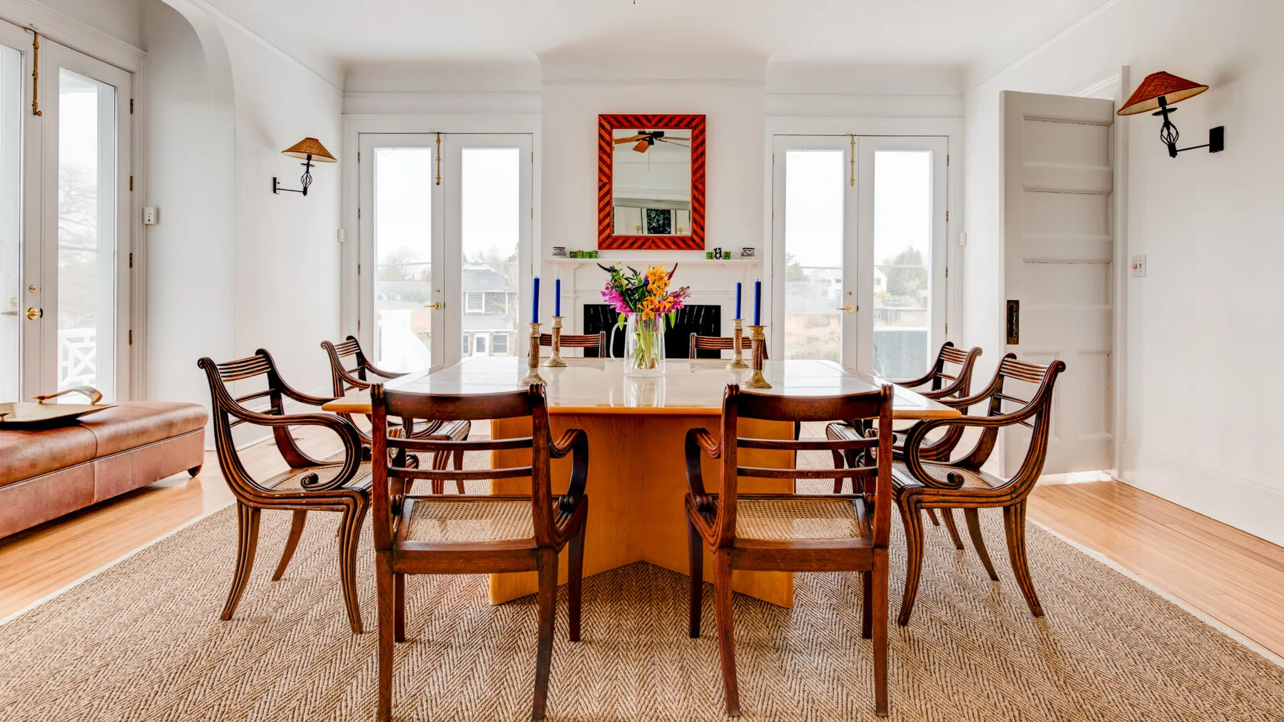 Un comedor luminoso con una mesa larga de madera y sillas tejidas.