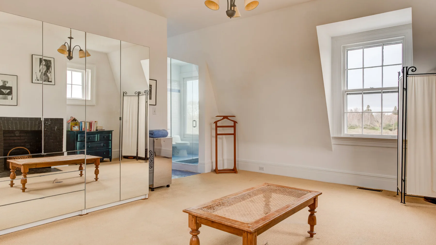 Un dormitorio luminoso con puertas de armario espejadas y una mesa de madera en el suelo.