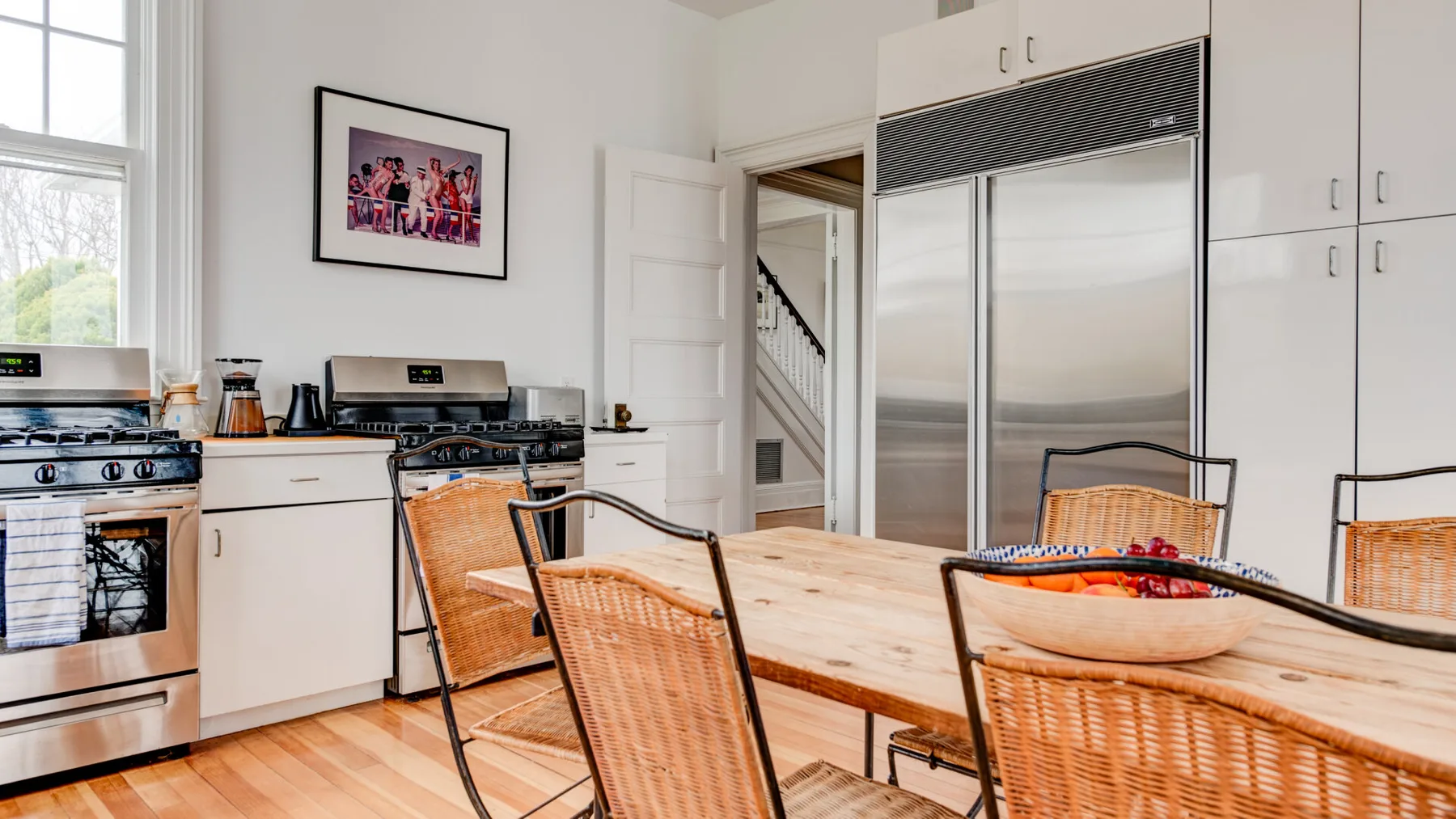 Una cocina y comedor luminosos con una mesa de madera y electrodomésticos de acero inoxidable.