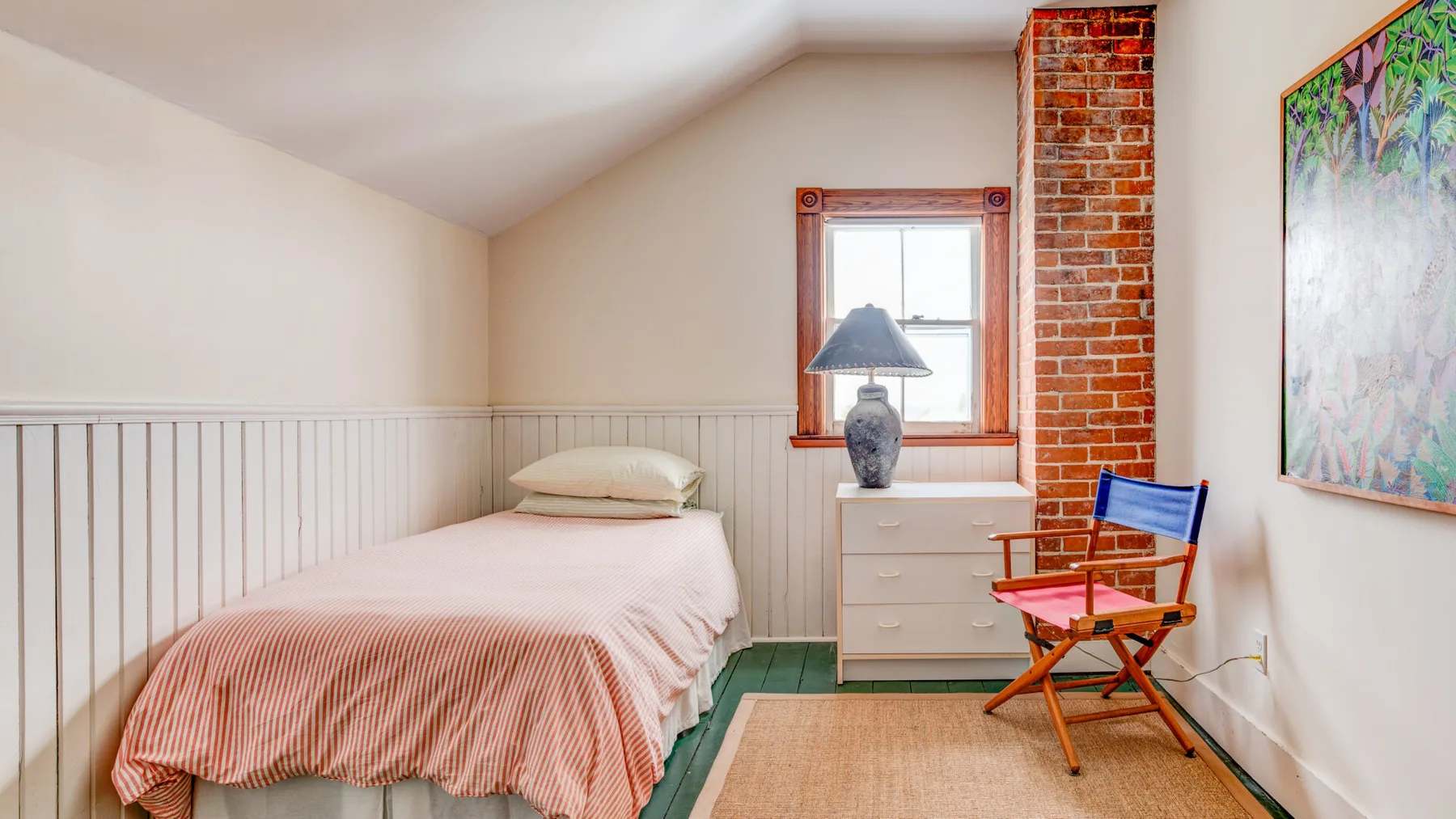 Un dormitorio con una cama individual, una cómoda y una ventana.