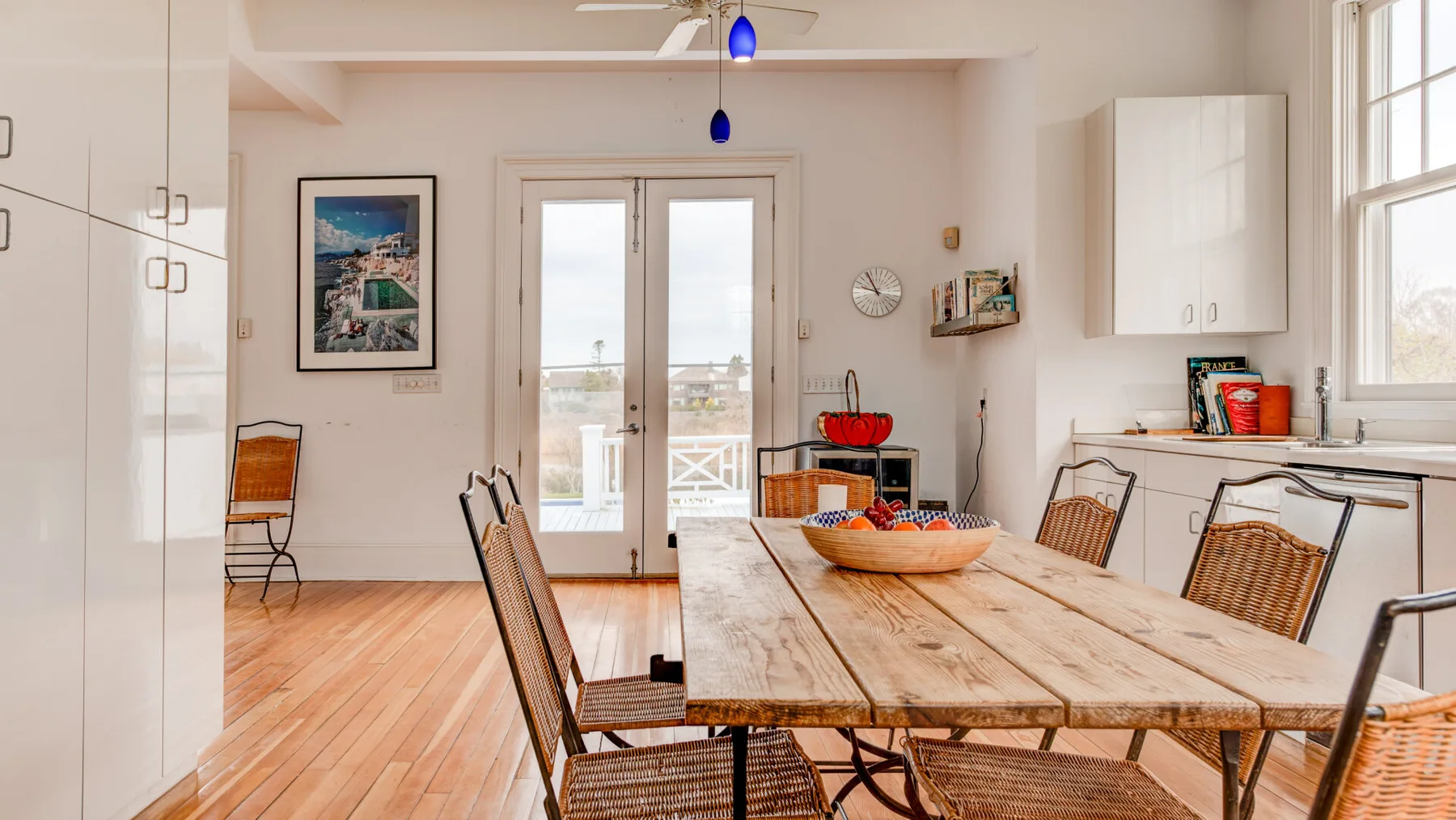 Un comedor luminoso con una mesa larga de madera y puertas de vidrio.
