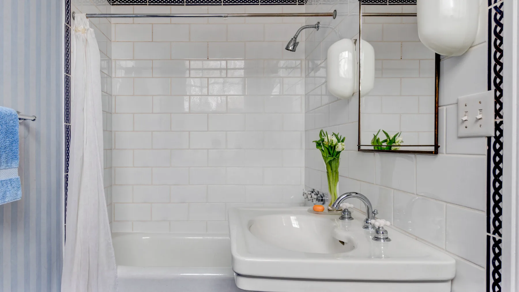 Un baño revestido de azulejos con bañera, cortina de ducha y lavabo.