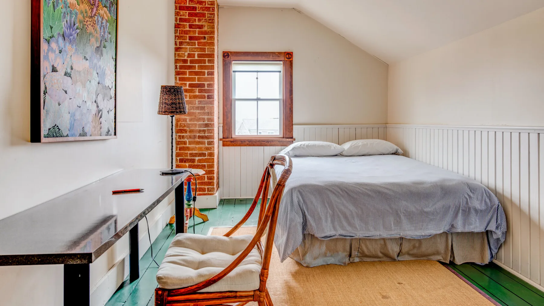 Un dormitorio abuhardillado luminoso con una cama bajo un techo inclinado.