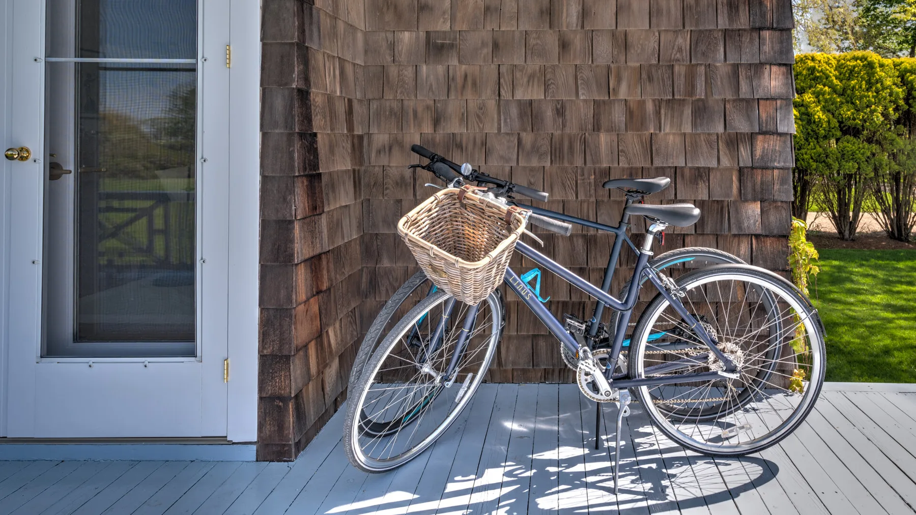 Una bicicleta con una cesta de mimbre está junto a la entrada de un edificio.
