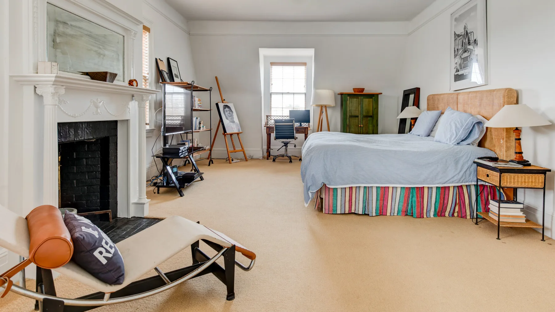 Un dormitorio luminoso con cama, chimenea y asientos.