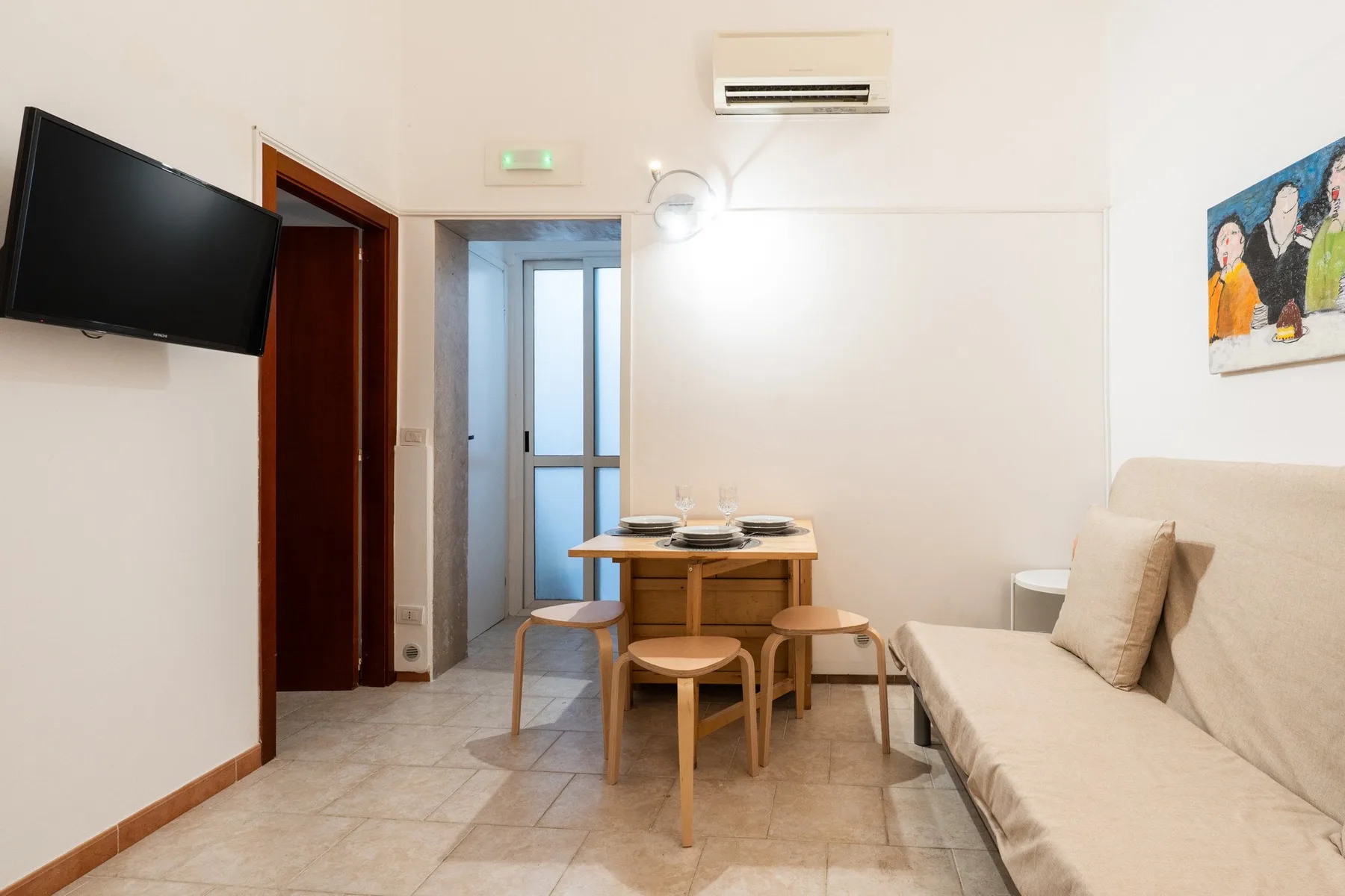 Una sala de estar y comedor con mesa, asientos y un televisor en la pared.