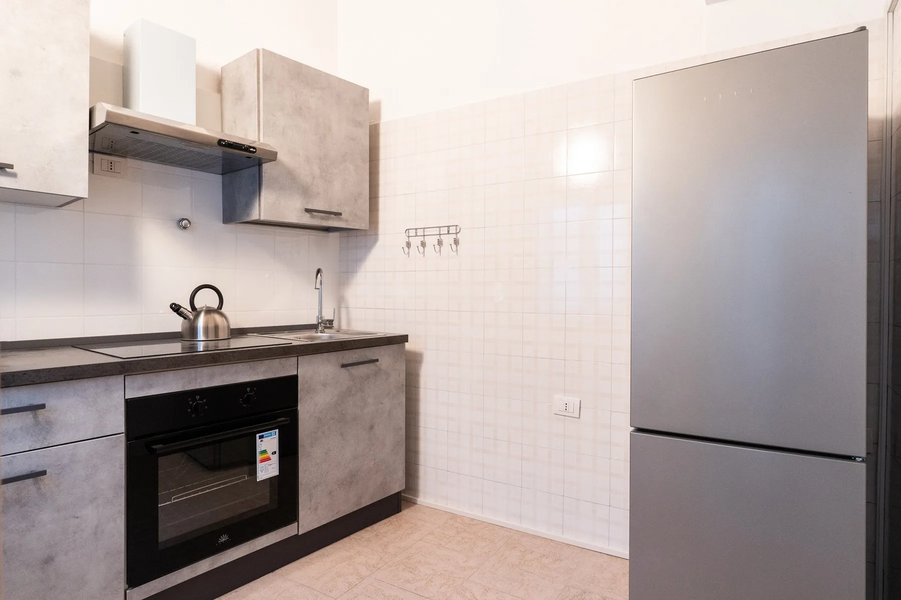 Una cocina compacta con gabinetes grises, una estufa y un refrigerador.