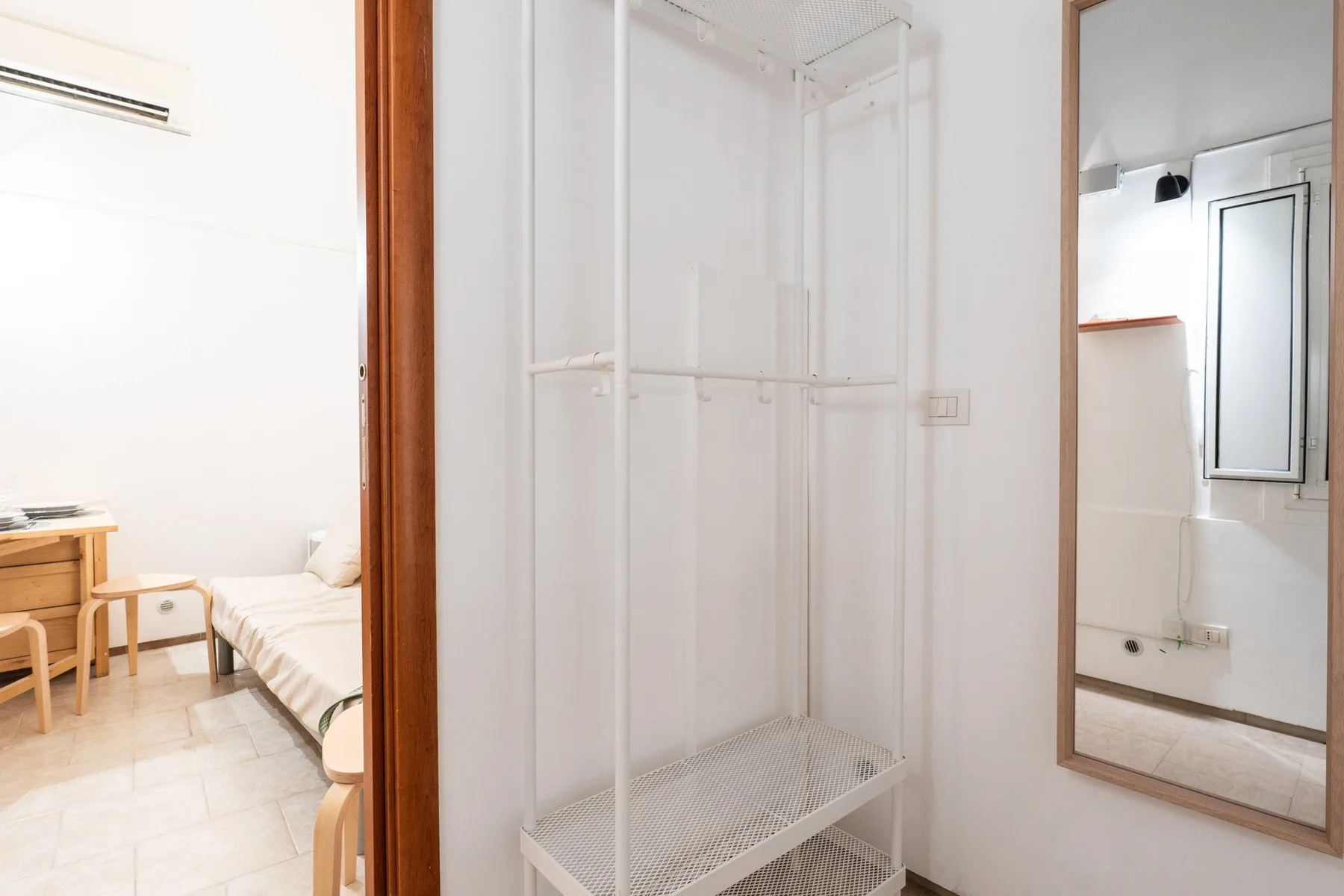 Un dormitorio con una cama y una estantería sencilla junto a la puerta.
