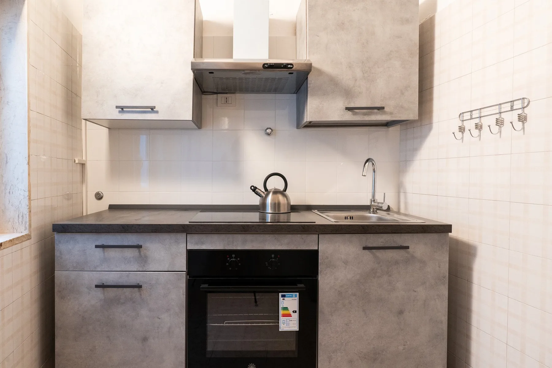 Una cocina compacta con gabinetes grises, encimera y horno integrado.