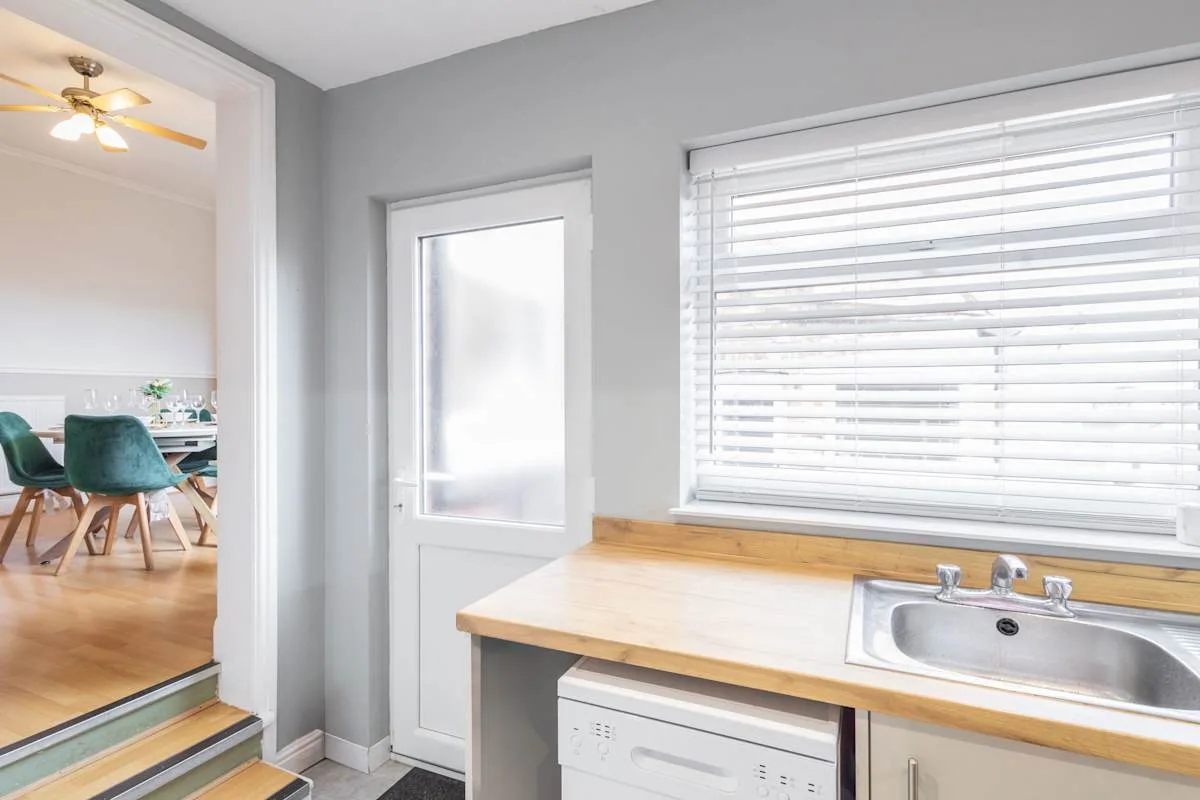 Una cocina luminosa con una encimera de madera, fregadero y ventana grande.