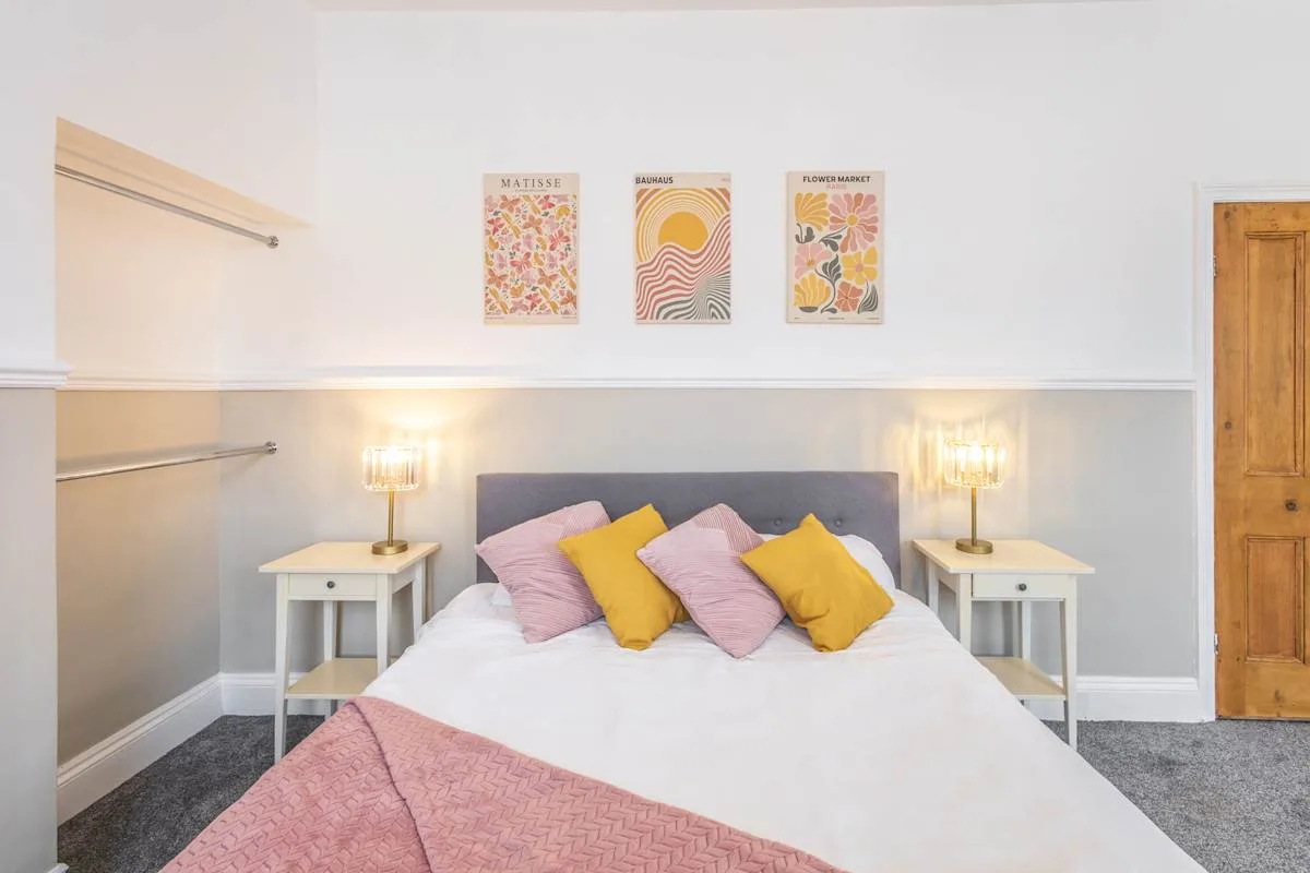 Un dormitorio con una cama, cojines de colores y mesillas a juego.