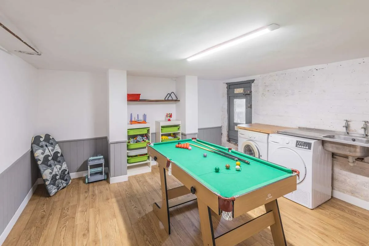 Una sala de recreación con una mesa de billar verde y estanterías.